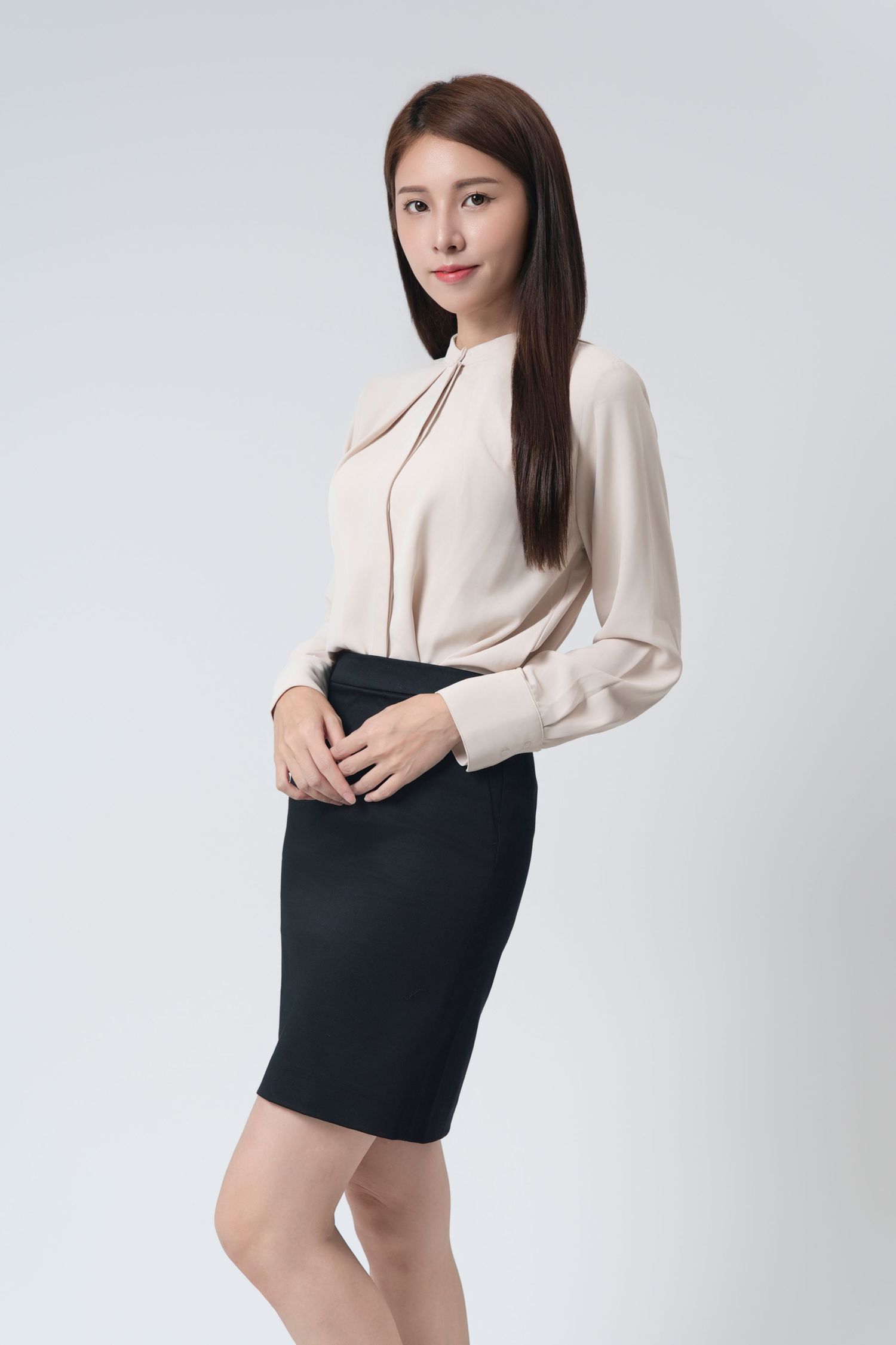 Professional business attire featuring a cream colored blouse and fitted black pencil skirt against light background.