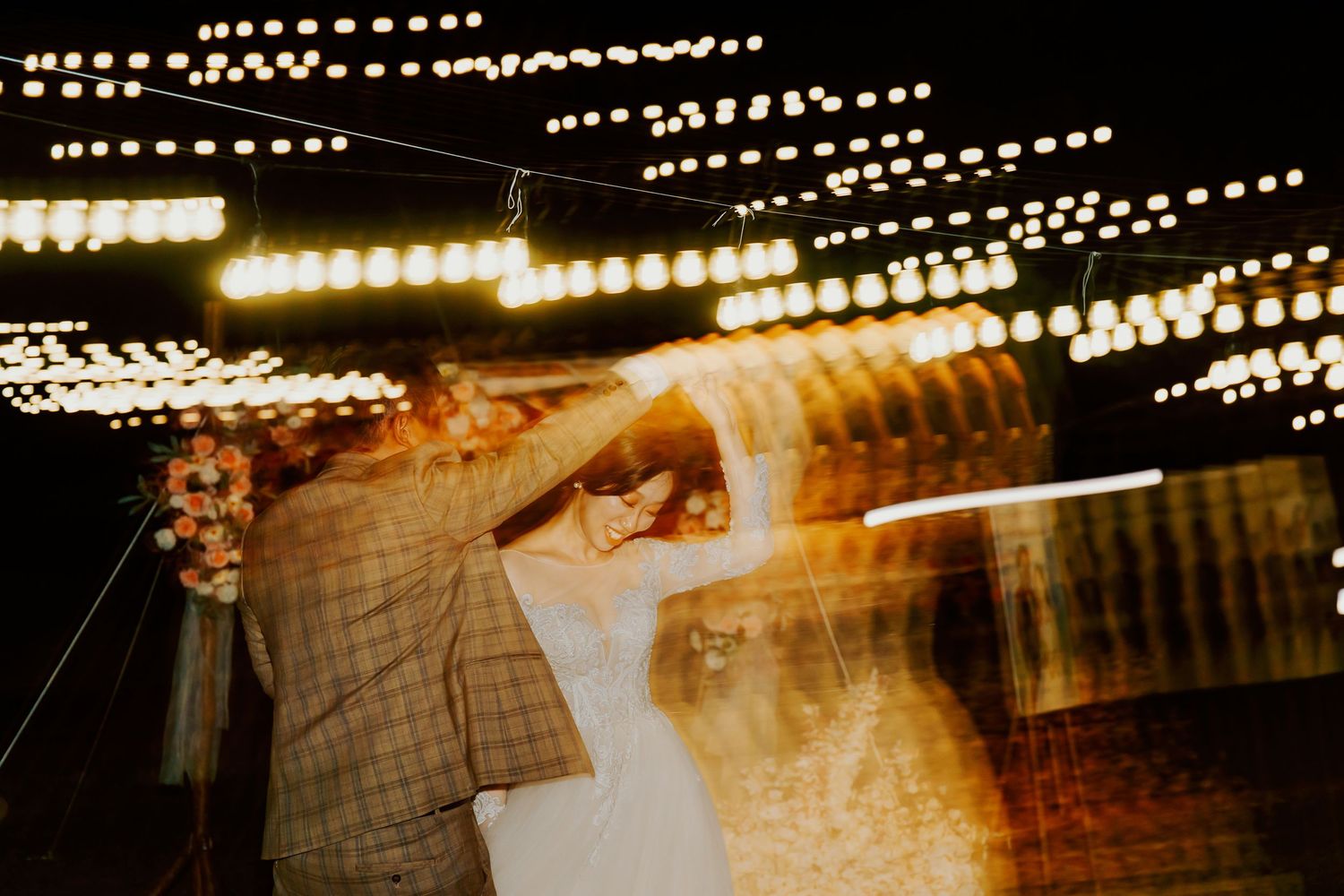 Rows of warm glowing string lights create a romantic ambiance across a dark evening sky at an outdoor venue.