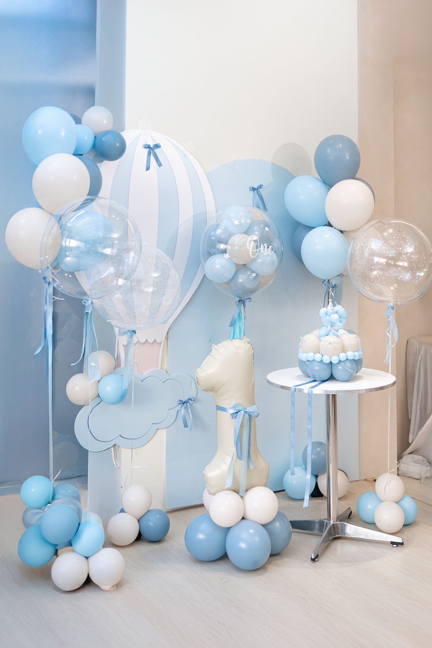 Baby blue and white balloon garland with cloud decorations creates a dreamy backdrop for a celebration or photo shoot.