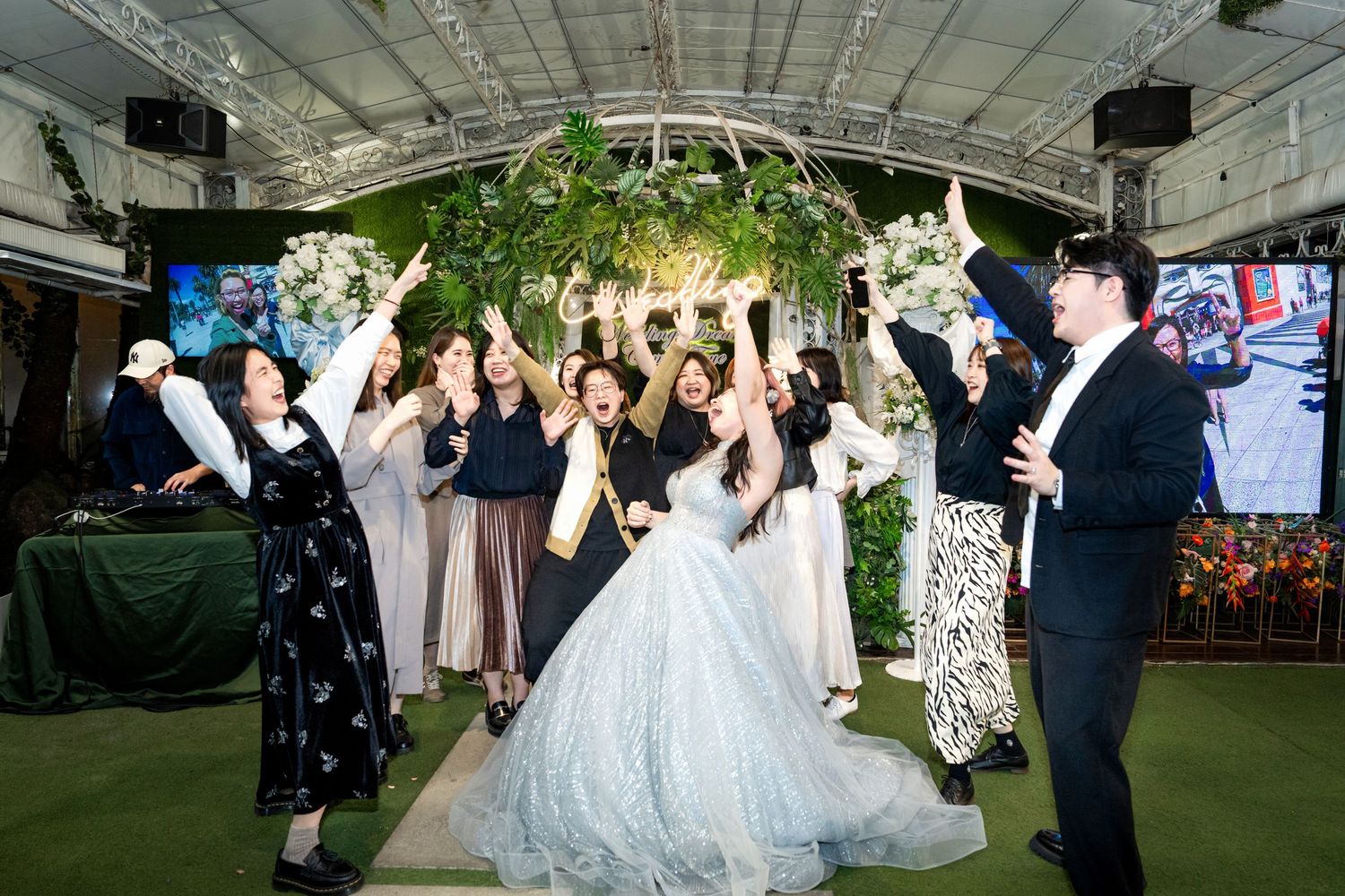 Wedding guests dance and celebrate on an illuminated dance floor during an elegant indoor-outdoor reception celebration.