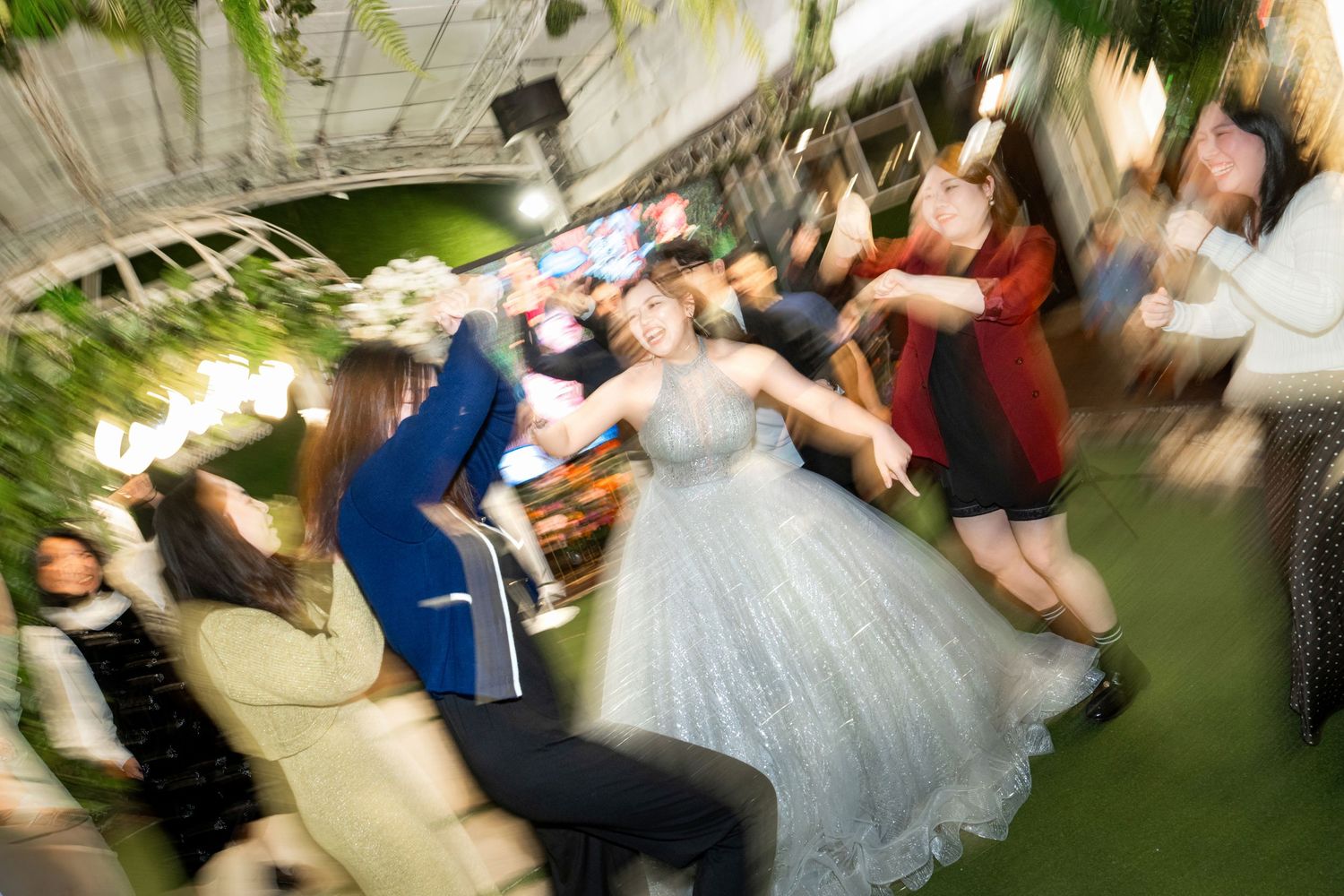 Wedding guests dance and celebrate together on a dance floor at a reception party.