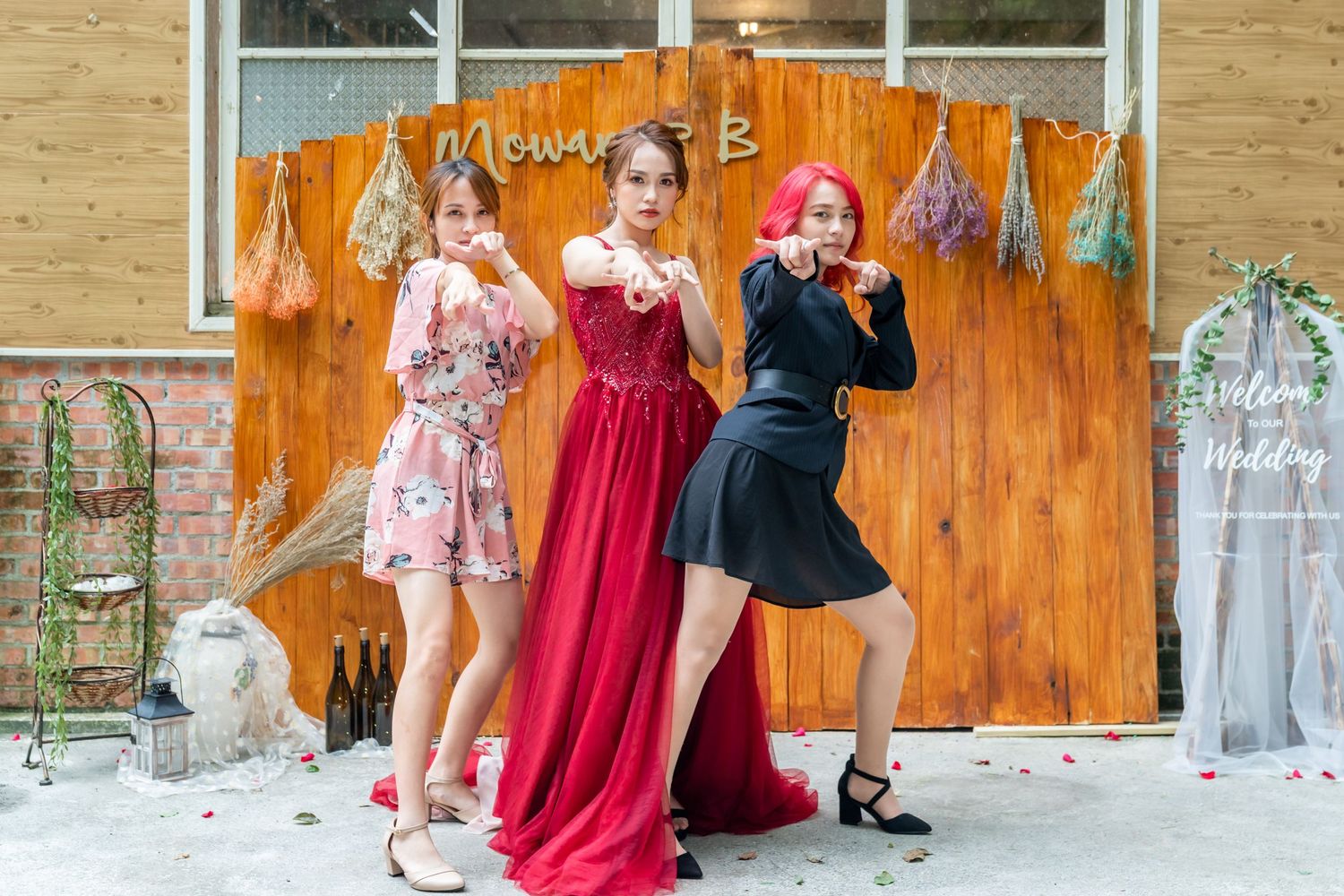 Models in floral, red and black outfits strike dynamic poses against a rustic backdrop.