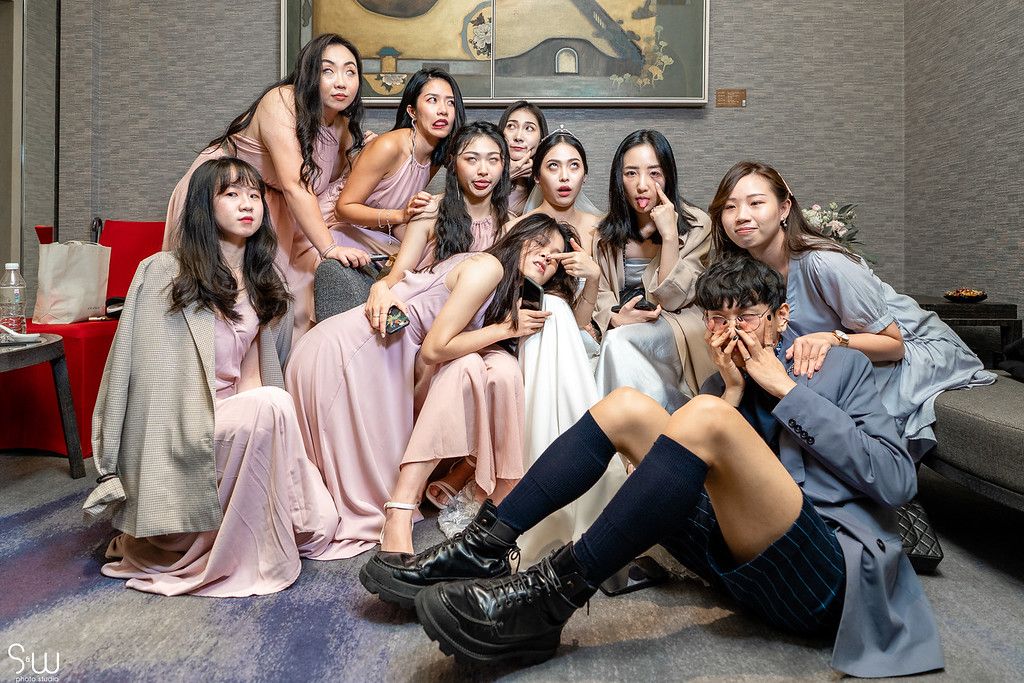 A group of bridesmaids in pink dresses pose casually together during wedding celebrations.