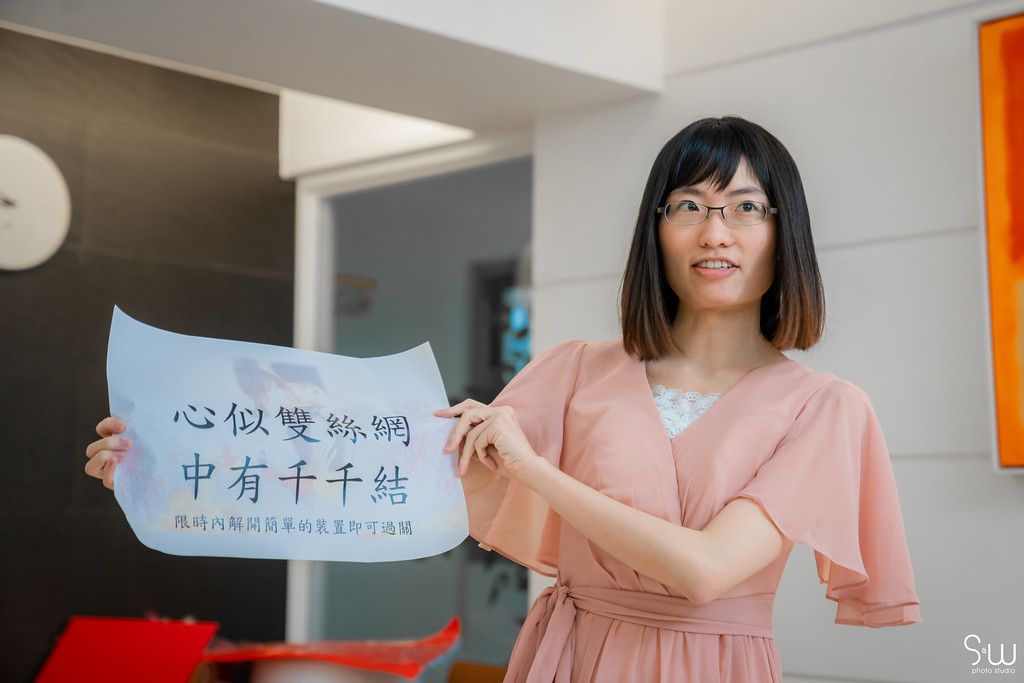Person in pink dress holding Chinese calligraphy sign during traditional wedding preparations.