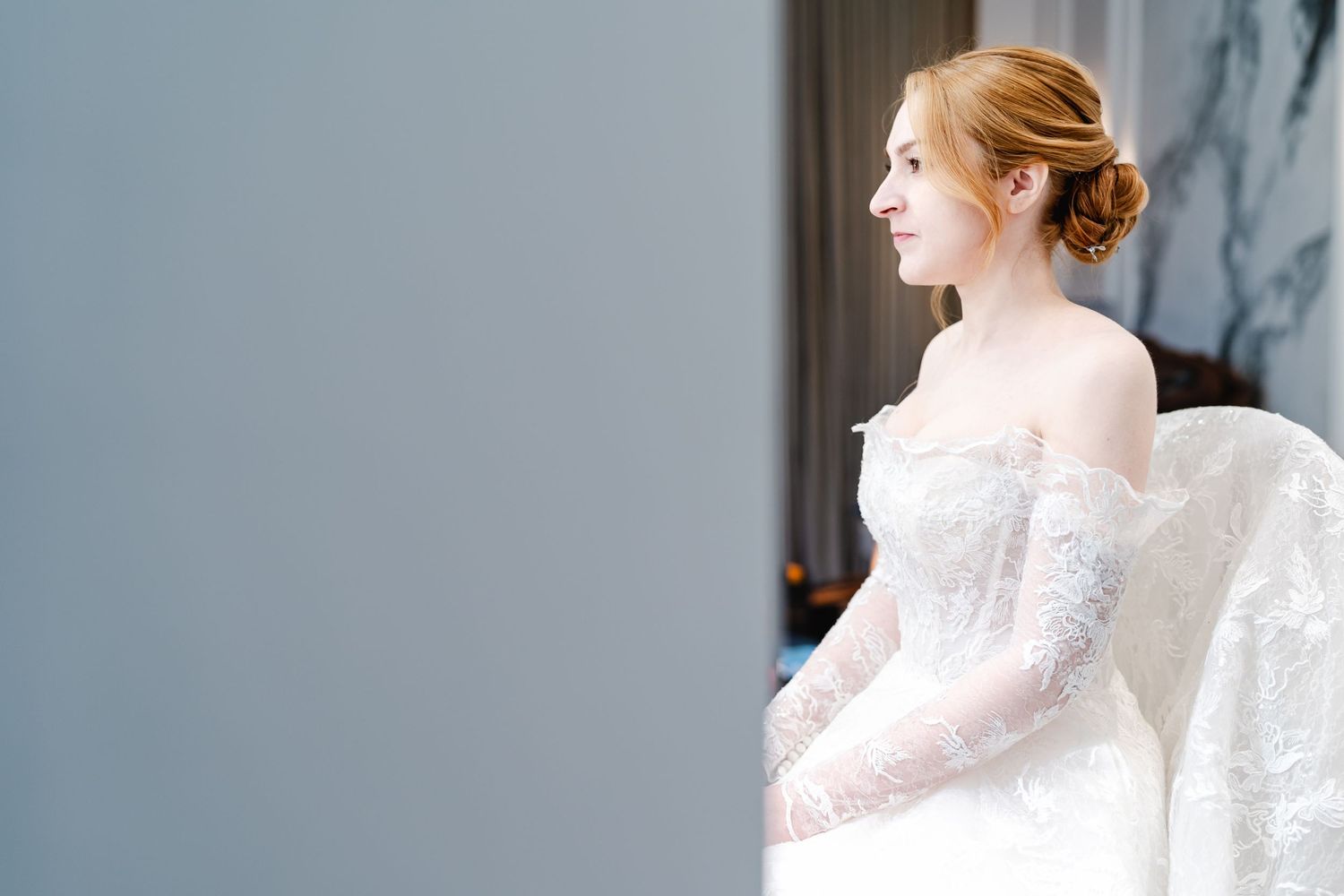 Elegant bridal preparation scene showing a white lace wedding dress in soft natural light.