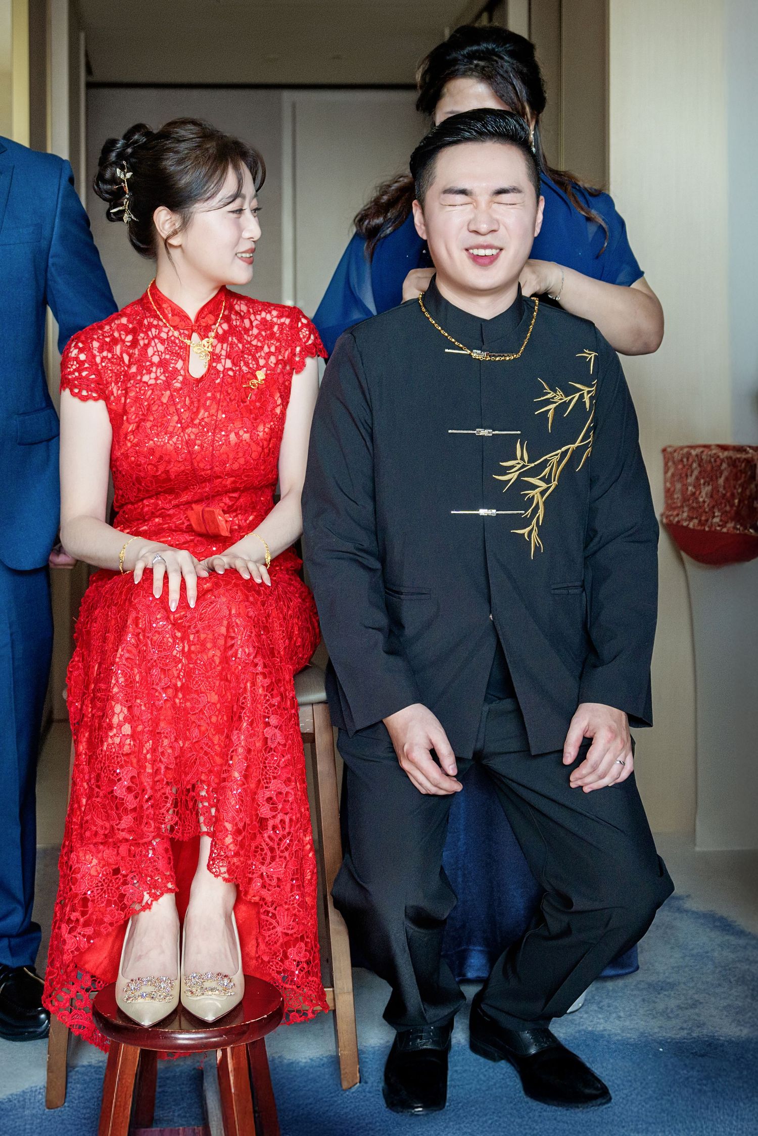A couple in traditional Chinese wedding attire, with the bride in red qipao and groom in black embroidered suit.