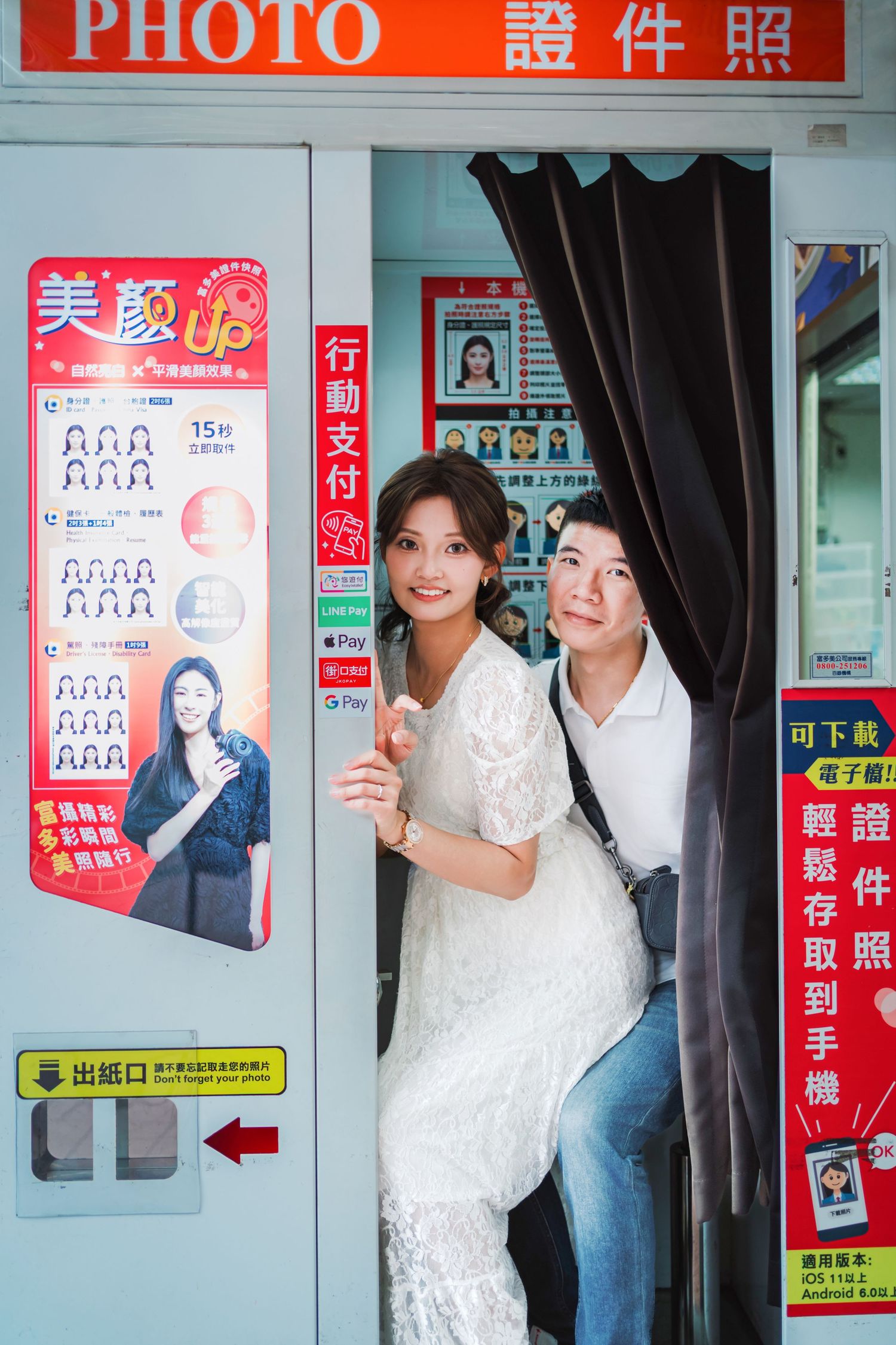 A photo booth with Chinese signage and colorful posters showing ID photo requirements and instructions.