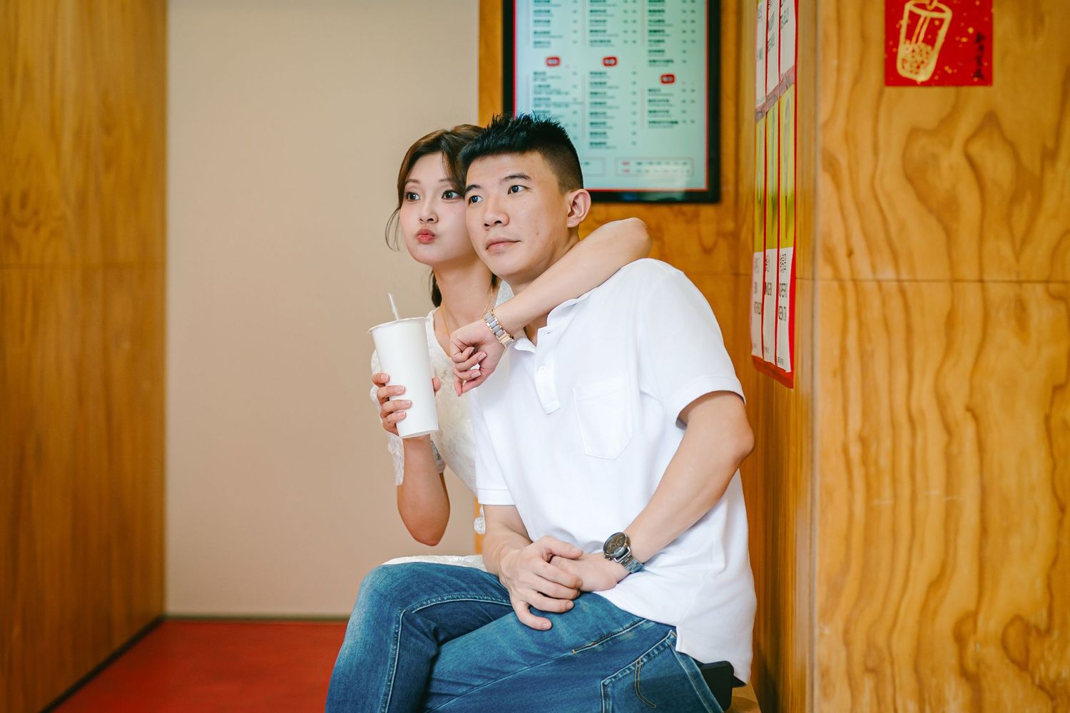 Two people in white t-shirts sit together on wooden steps while sharing a meal and talking.