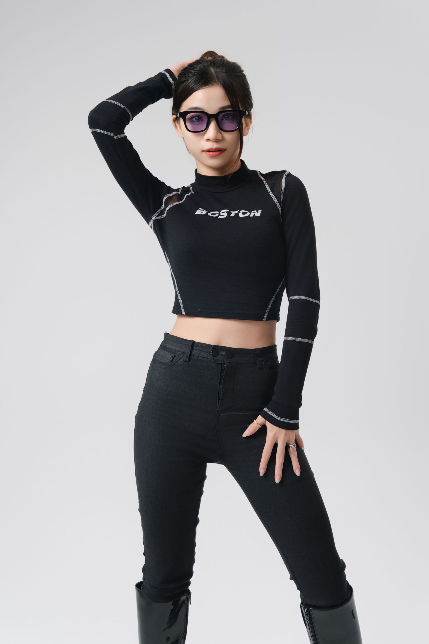 Athletic figure in black crop top and high-waisted pants poses confidently against white background.