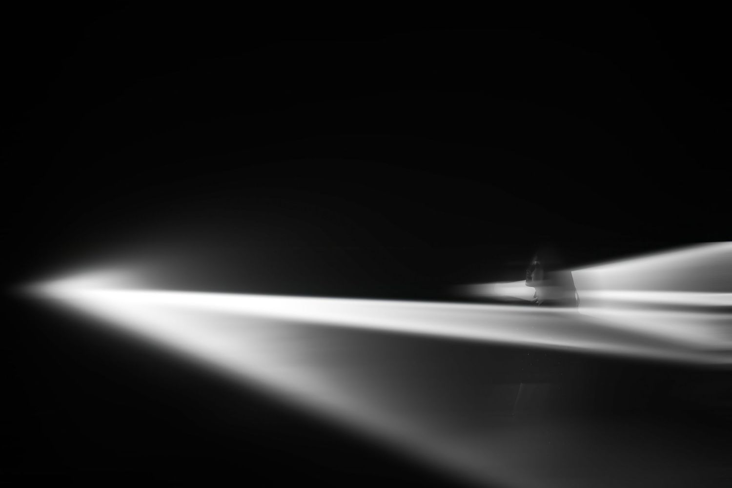 Black and white photo of a vinyl record player with dramatic light beams streaking across a dark background.