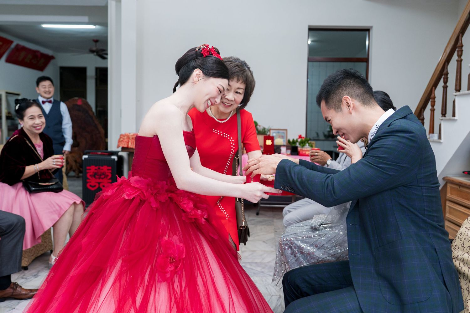 Bride in red gown and groom exchange rings during traditional Chinese wedding ceremony indoors.