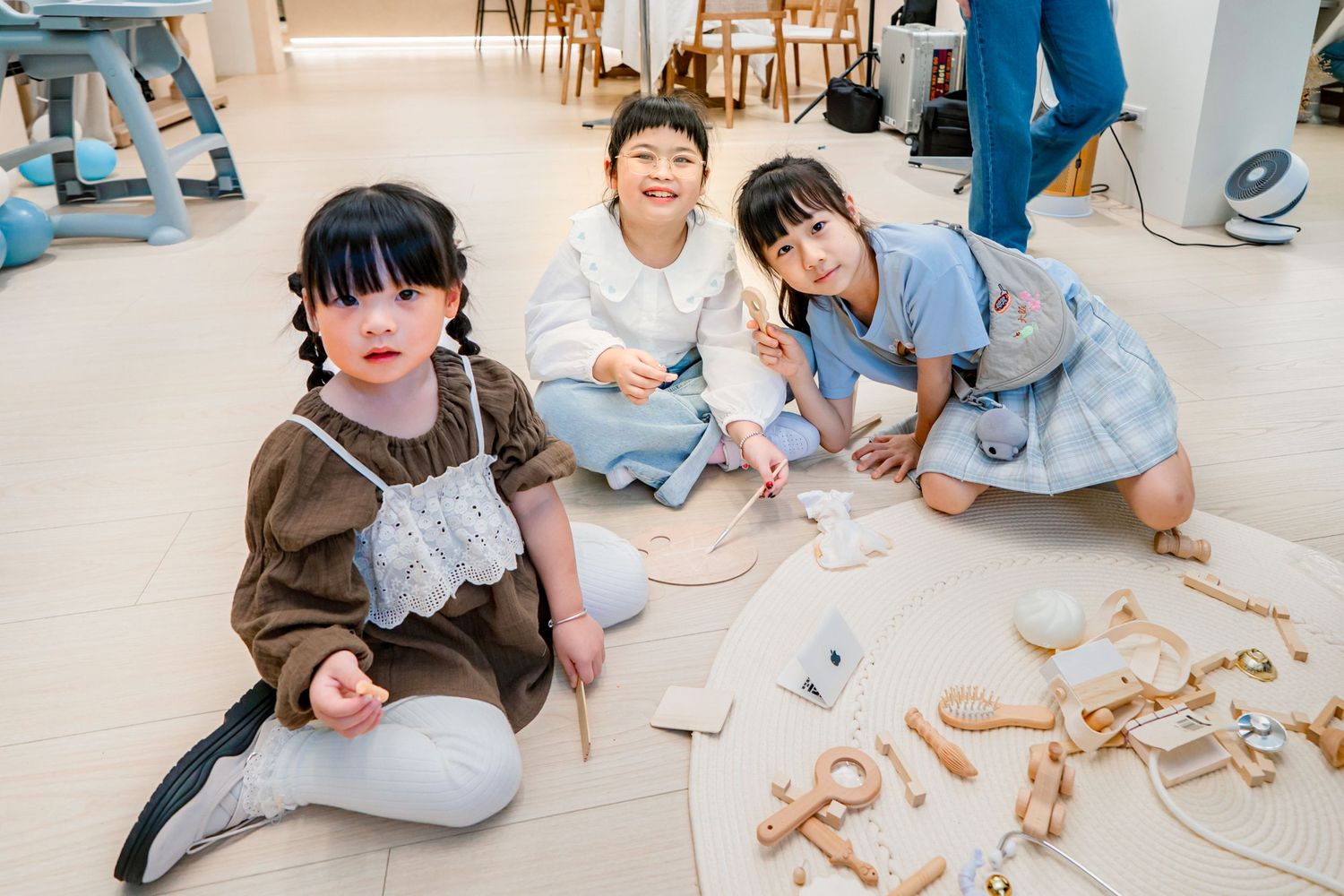 Children sitting on the floor working together with wooden building blocks and construction toys in an educational setting.