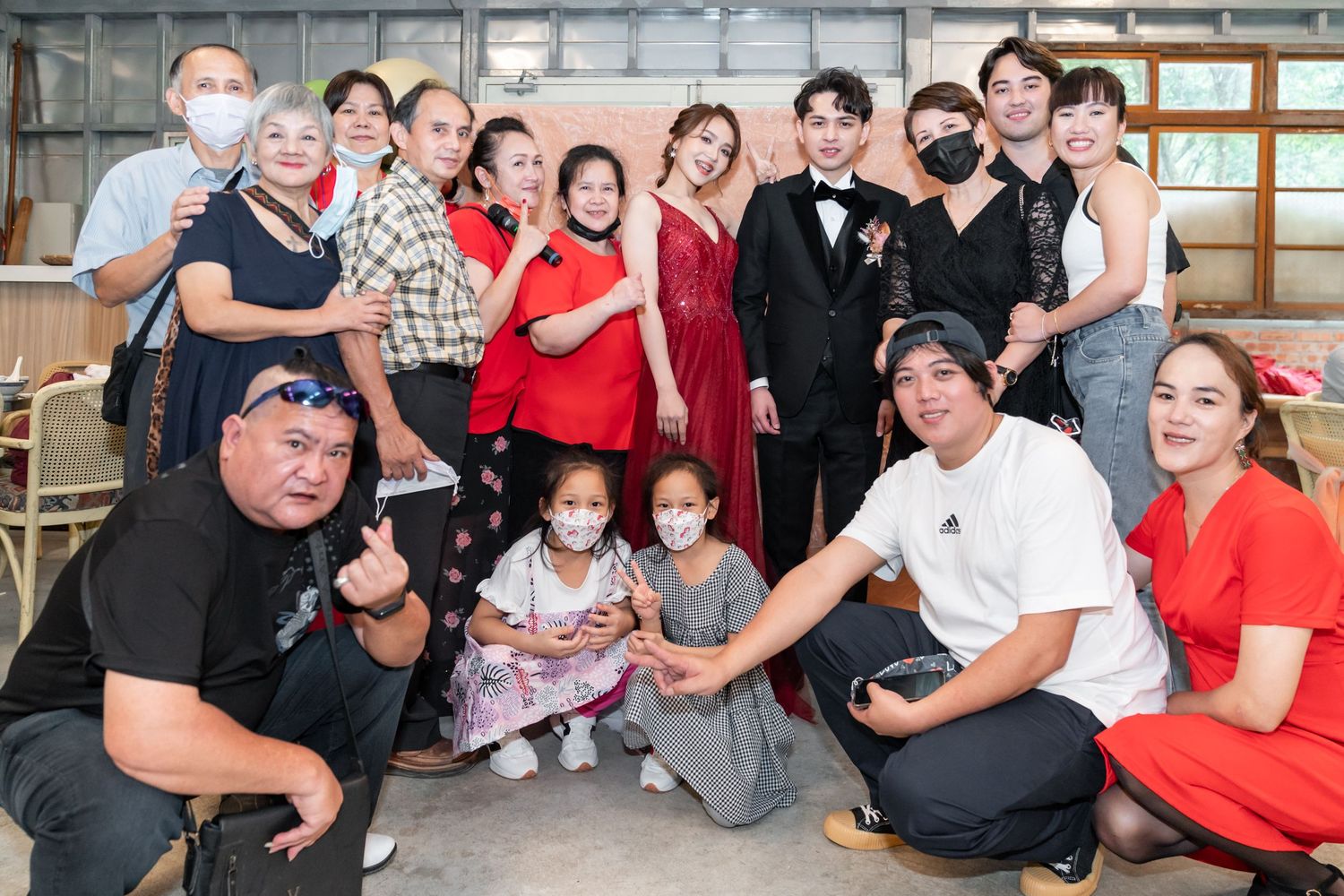 A cheerful group poses together at an indoor event wearing masks and formal attire.