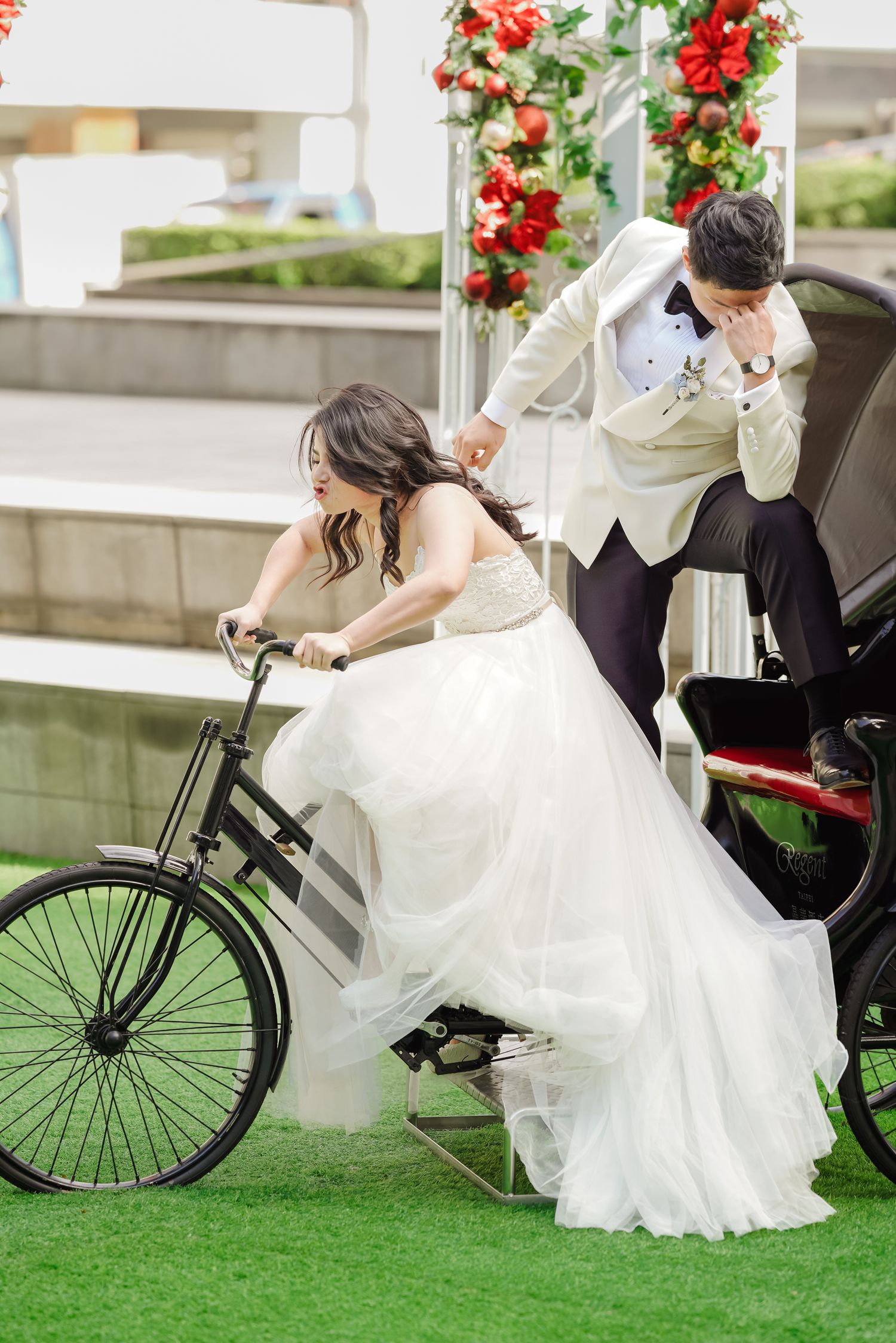 Playful wedding couple with bride on vintage bicycle and groom in light colored suit.