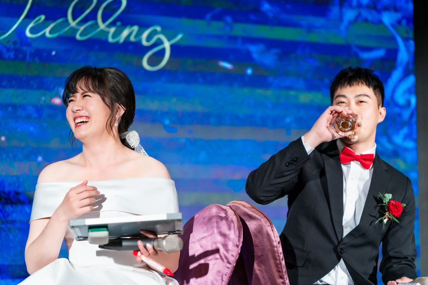 A couple laughs while participating in drinking games at their wedding reception.