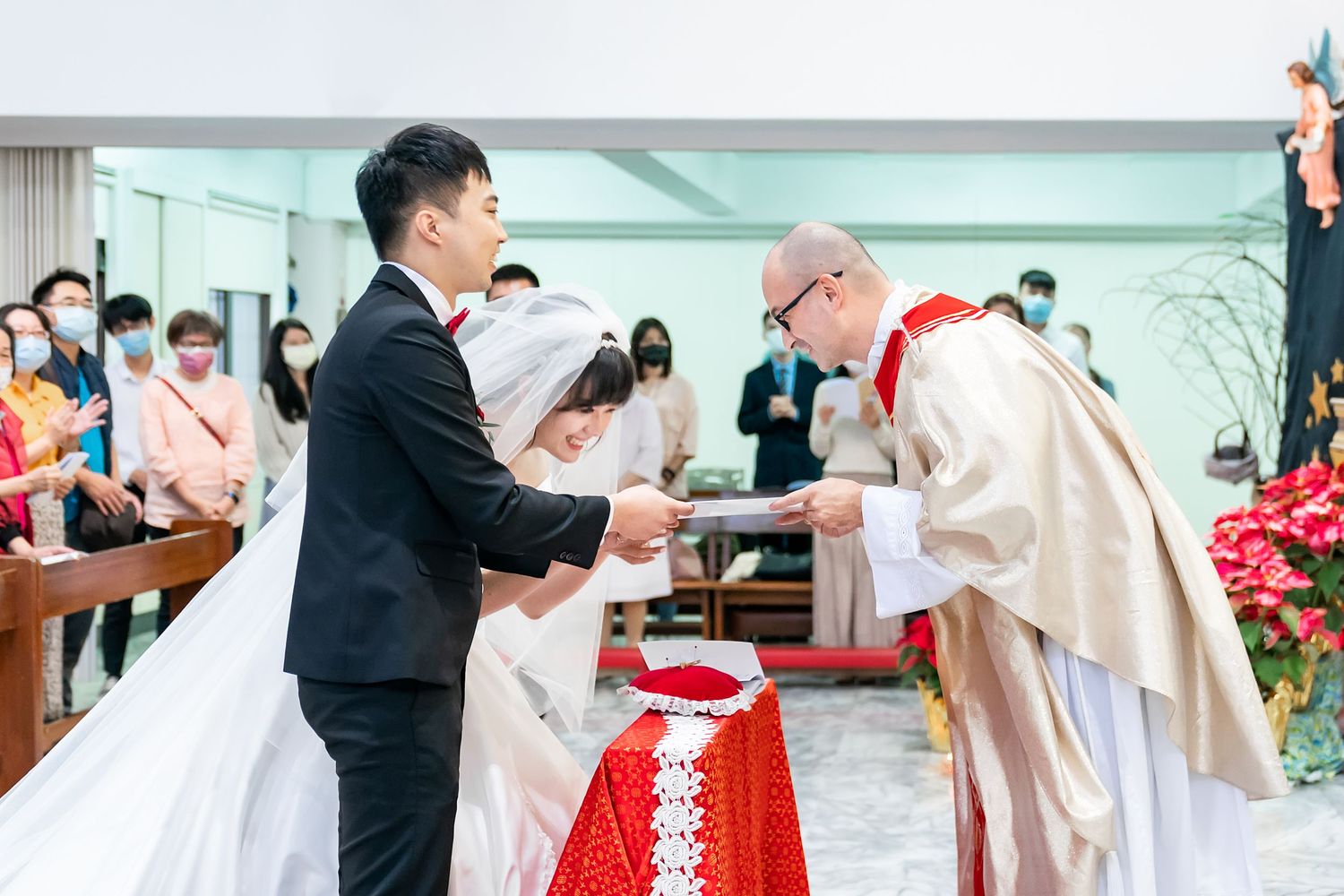 Priest performs blessing during wedding ceremony at decorated church altar.