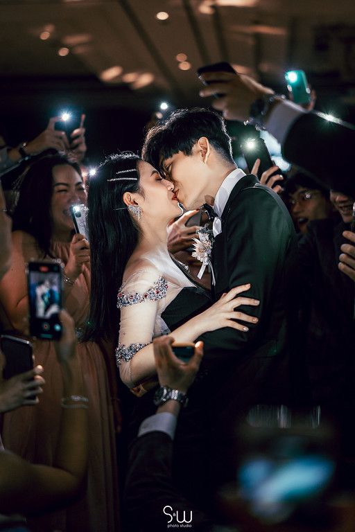Romantic moment captured during wedding reception with phone lights illuminating the couple.
