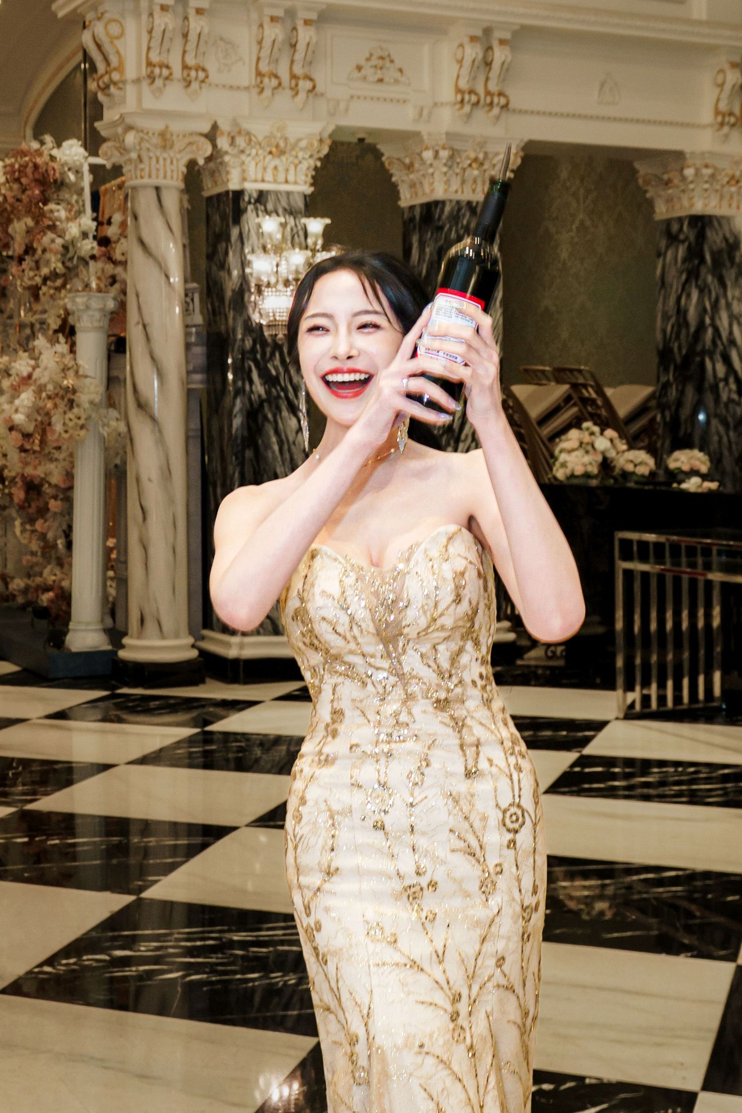 A joyful moment captured in a gold sequined dress against an elegant black and white checkered floor.