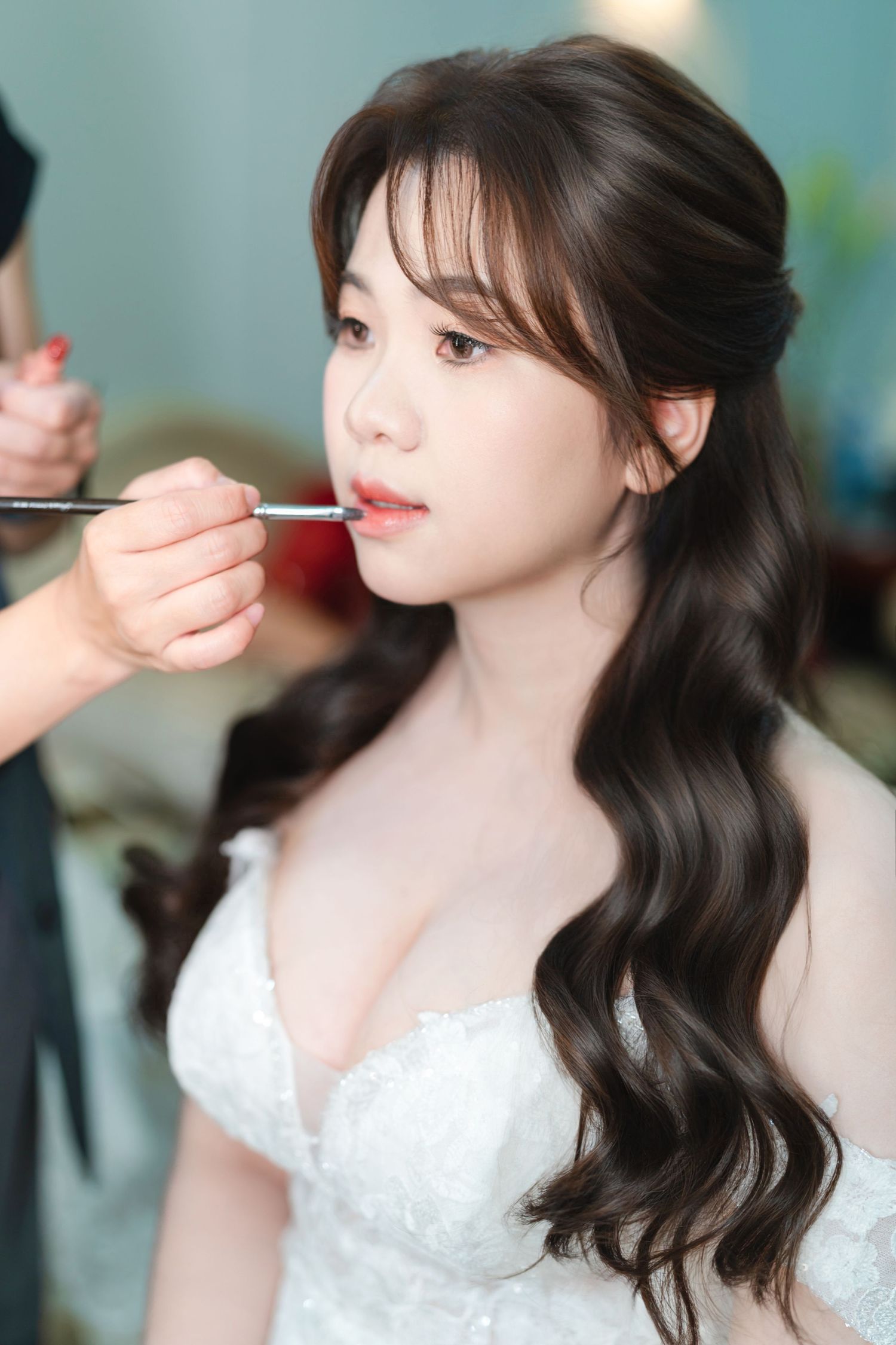 A bridal preparation scene shows long dark wavy hair and white lace dress while makeup is being applied.