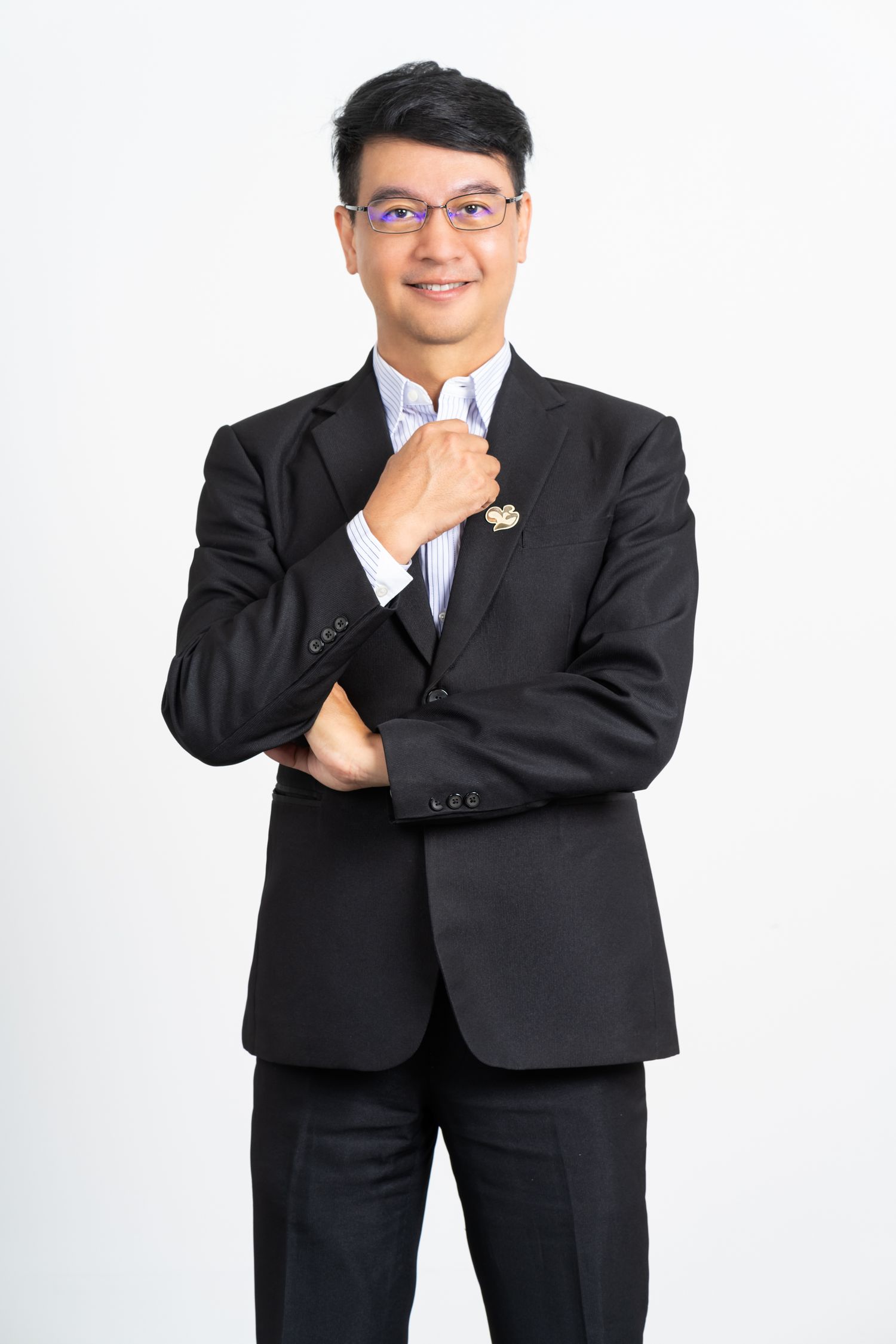 Professional portrait of person in dark business suit adjusting tie against white background.
