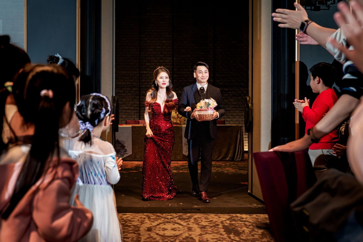 Wedding party dances together during reception in elegant ballroom with ornate carpet and lighting.