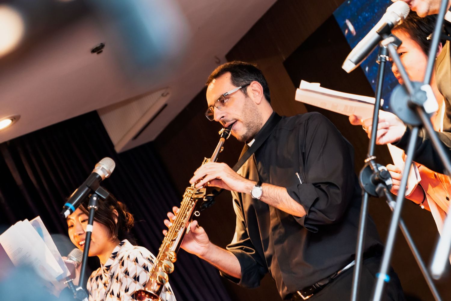 Musicians perform on stage with clarinet and other instruments during a live jazz performance.