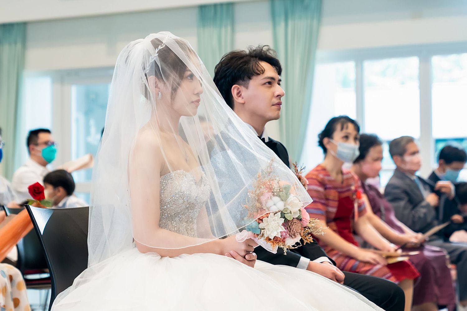 Wedding ceremony participants seated in a modern church setting.