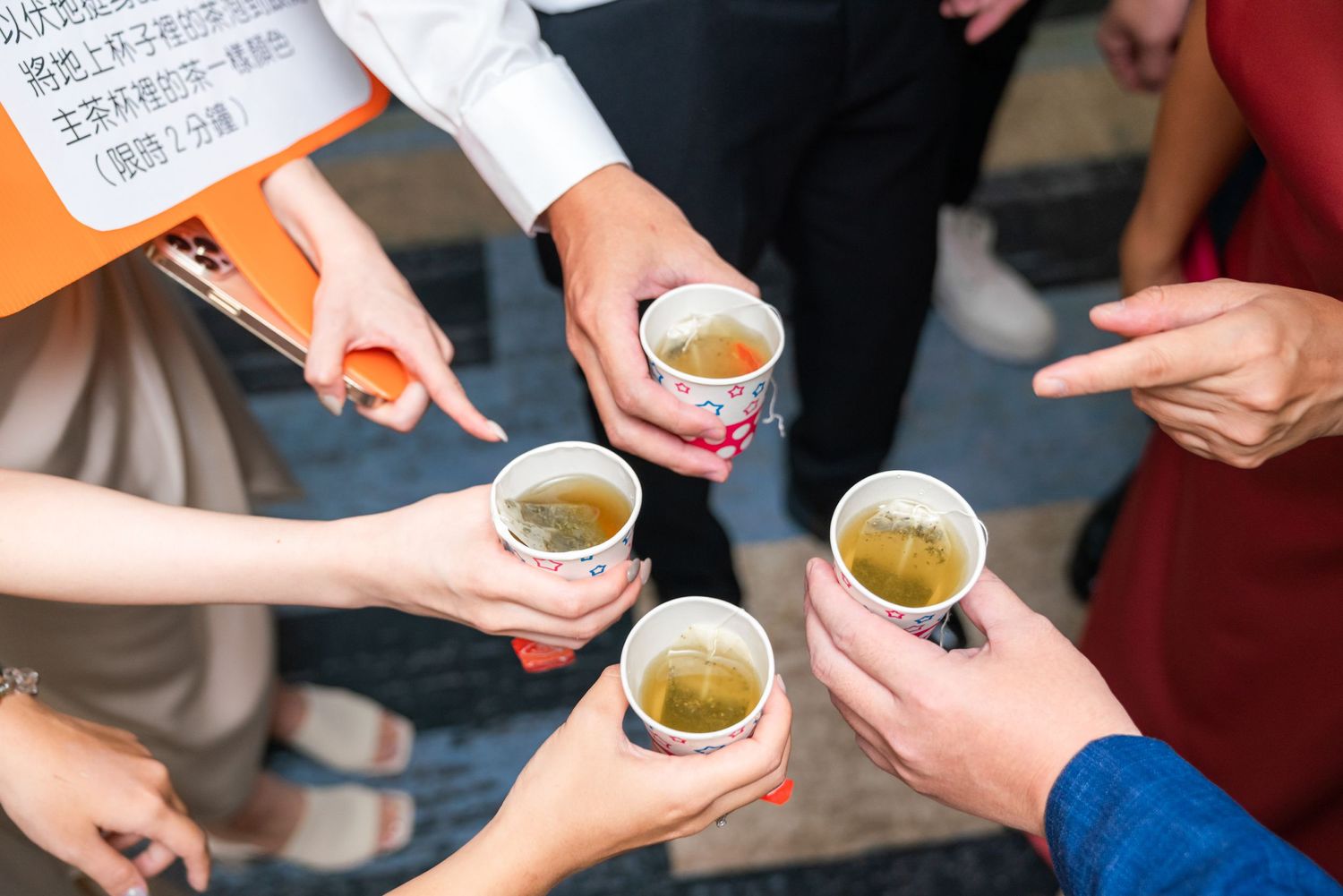 Four people hold small ceramic cups filled with green tea during a social gathering.