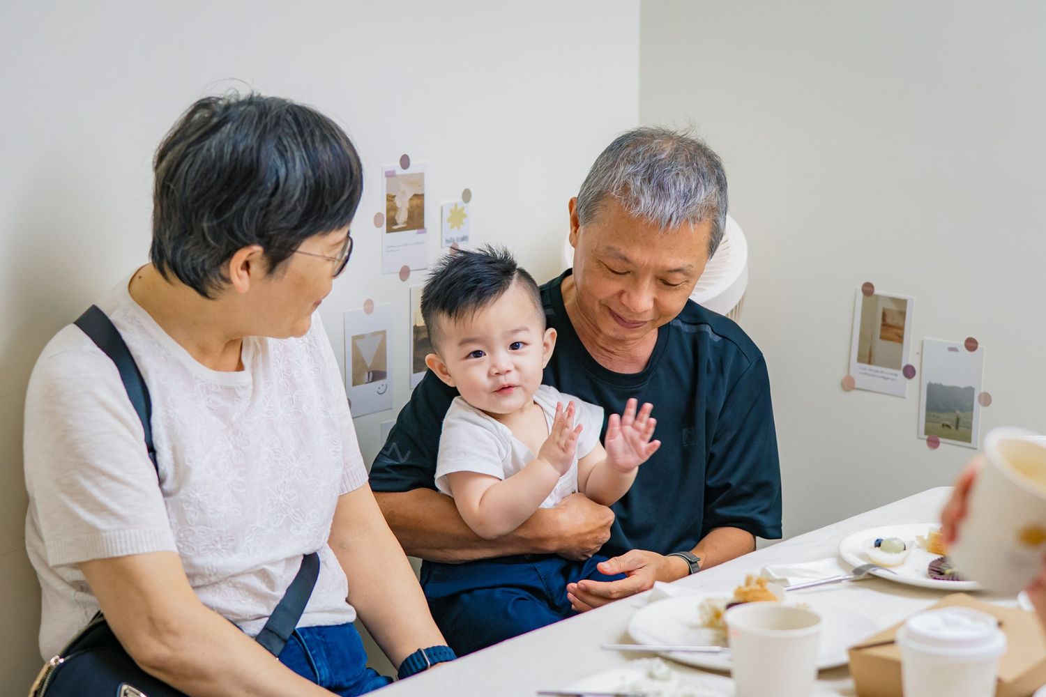 Family members sit together at a table enjoying a meal and conversation in a bright white dining room.