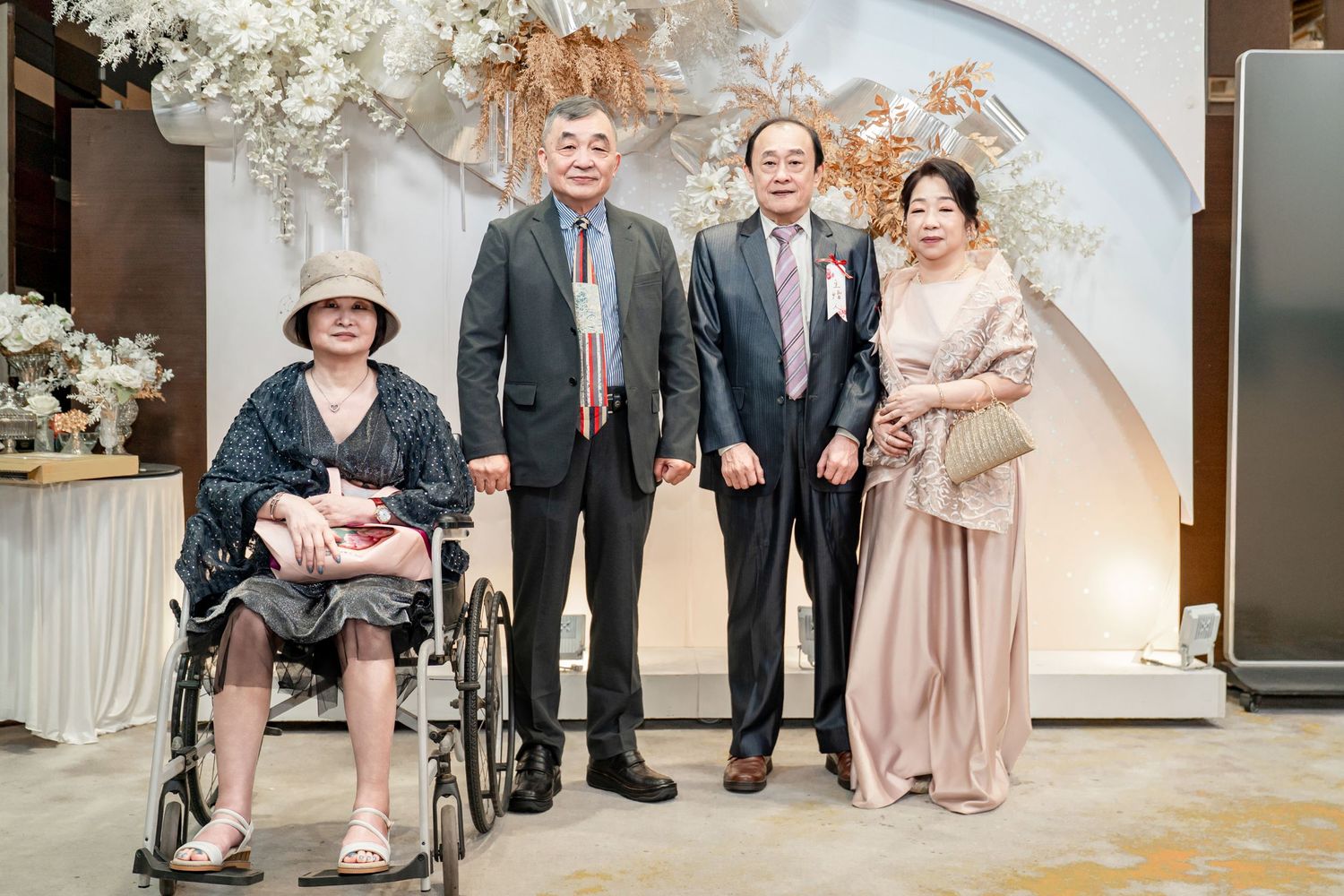Wedding guests gather together in formal attire for a series of group photos in an elegant indoor venue.