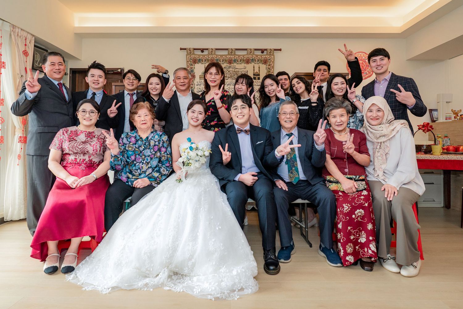 Wedding party members pose together in a modern indoor venue with warm lighting and white decor.