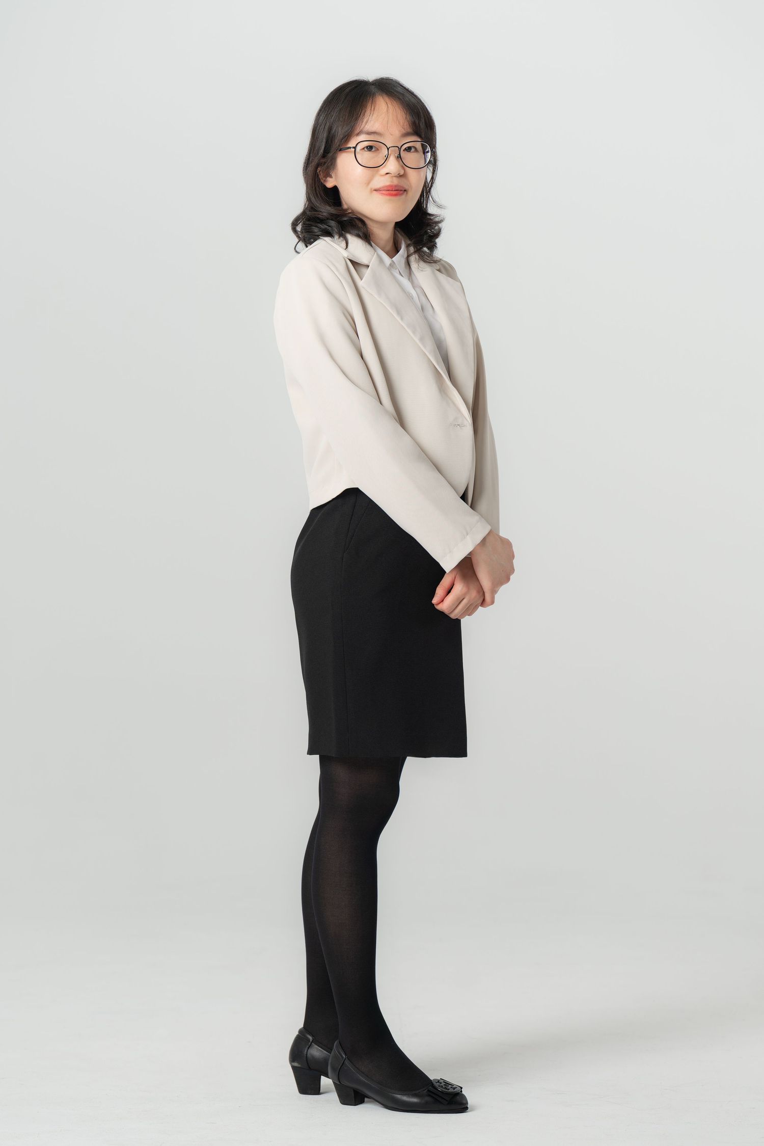 A person in a cream sweater and black pants poses against a light background in a series of fashion photos.