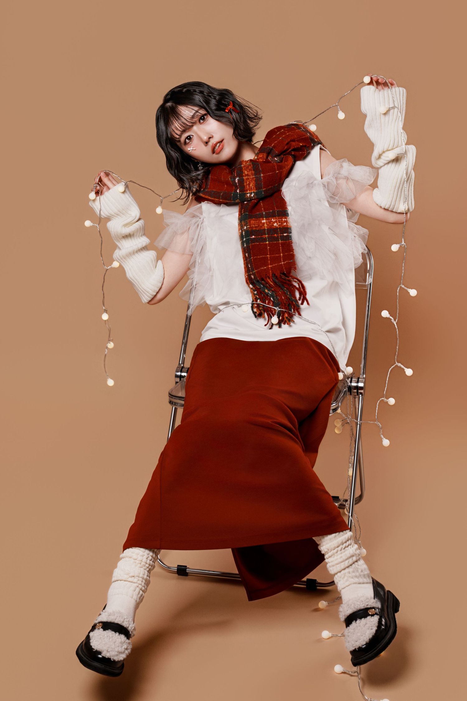 A fashion series showing a model in a red jumper dress and white blouse with plaid scarf in various playful poses.