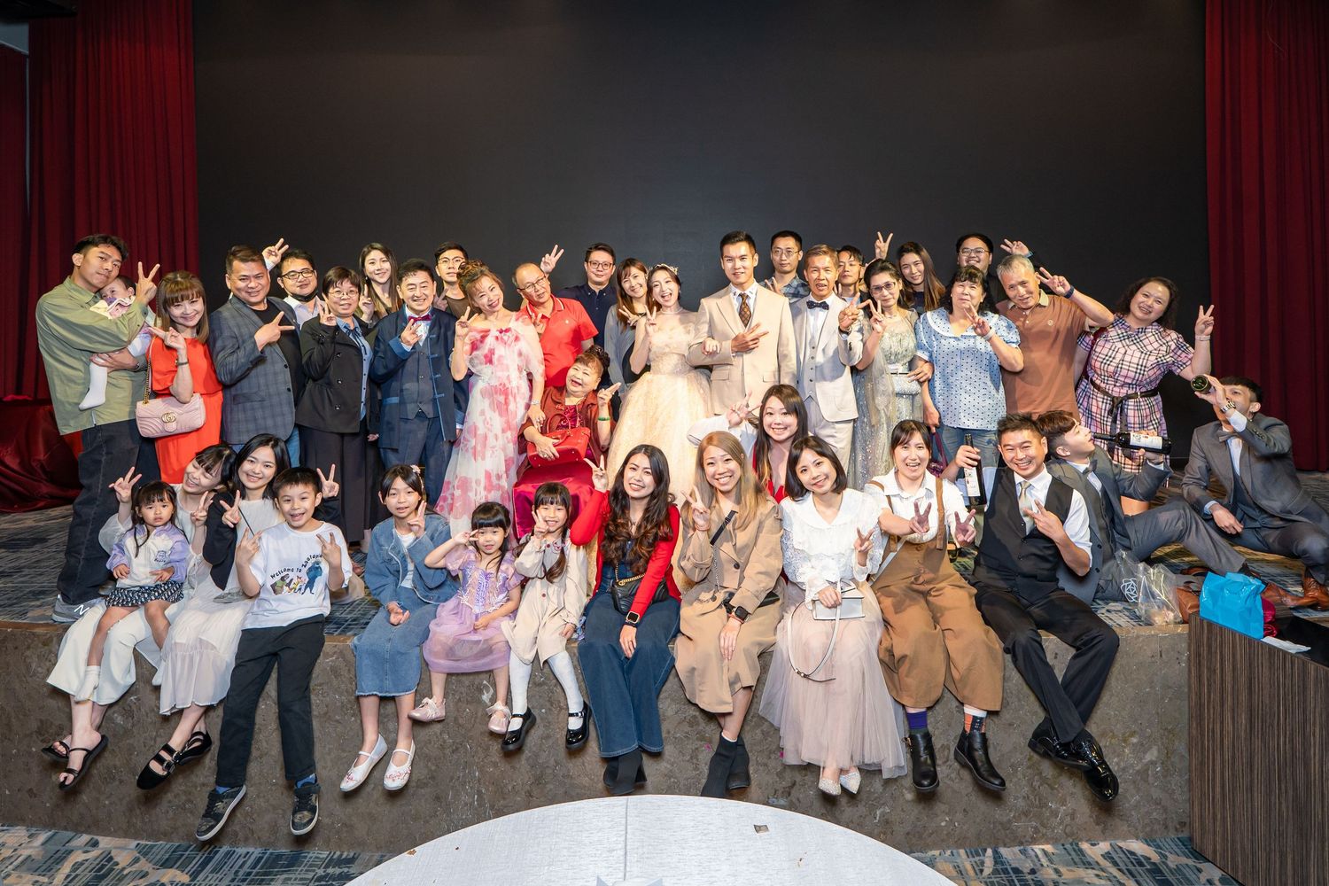 Large group of elegantly dressed adults and children posing together for a celebratory photo at a formal event.