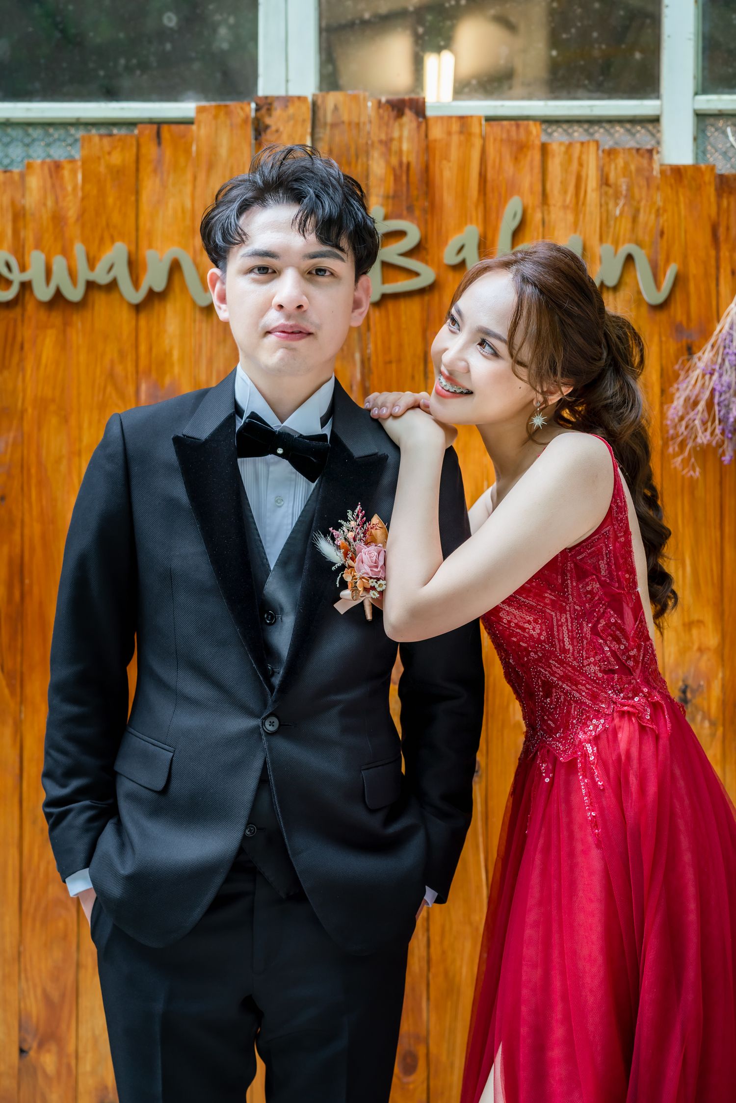 Stylish formal portrait session against wooden wall with decorative elements.