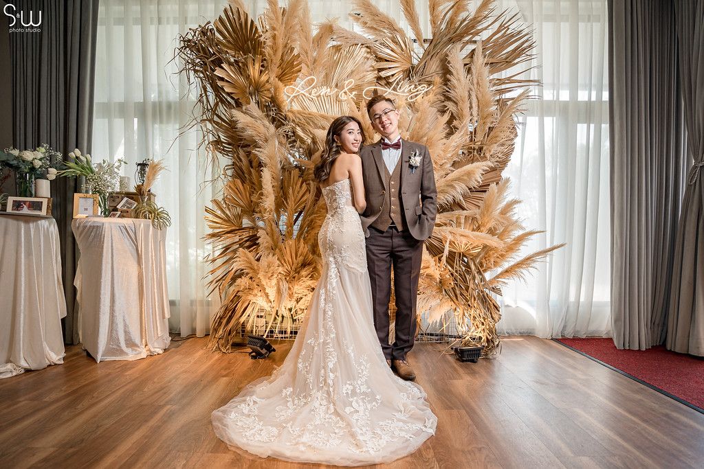 Elegant wedding portrait against dramatic dried palm fan backdrop in neutral tones.