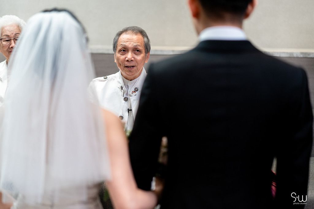 Wedding officiant conducts marriage ceremony for couple in traditional attire.