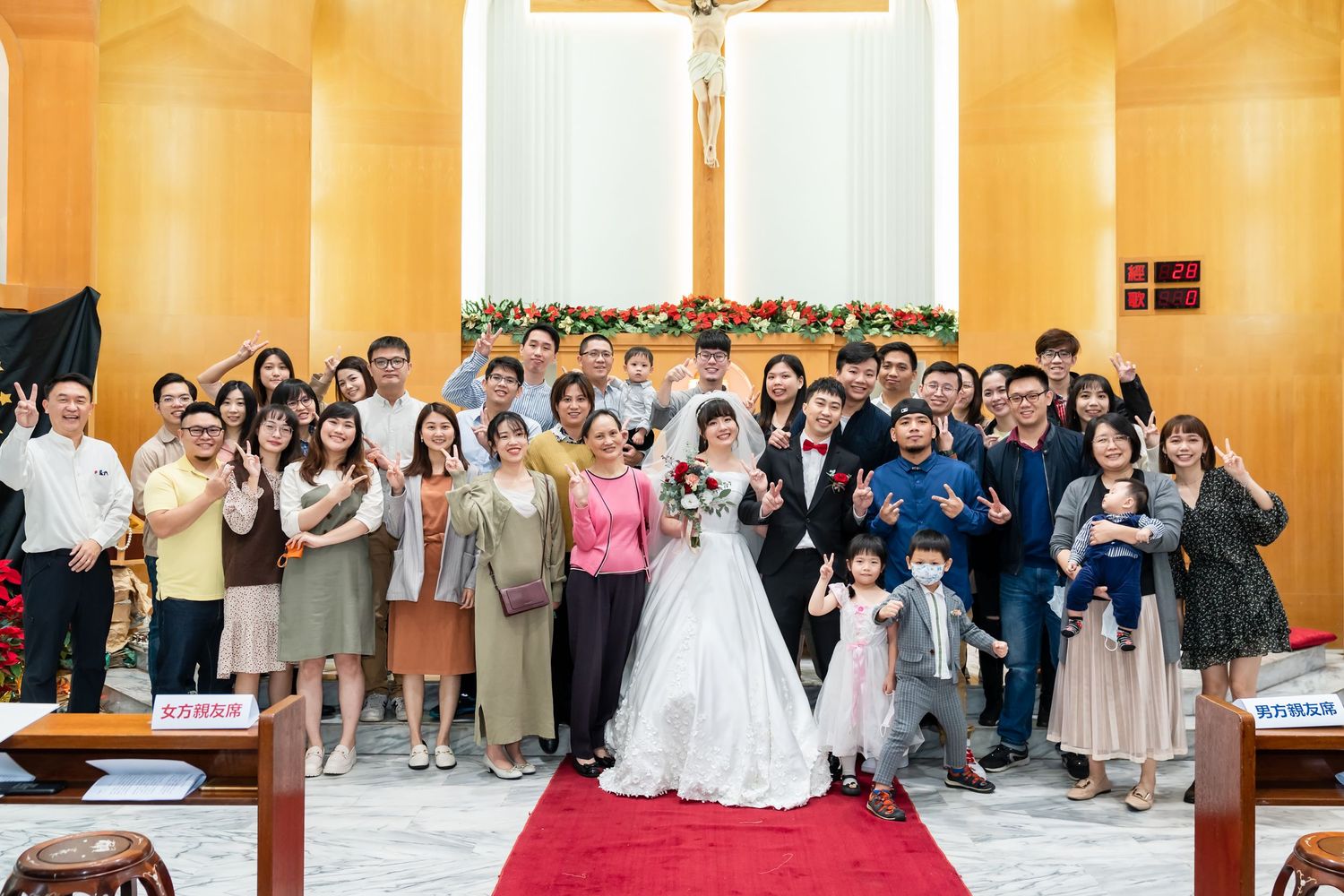 Celebratory wedding gathering with guests on red carpet in church sanctuary.