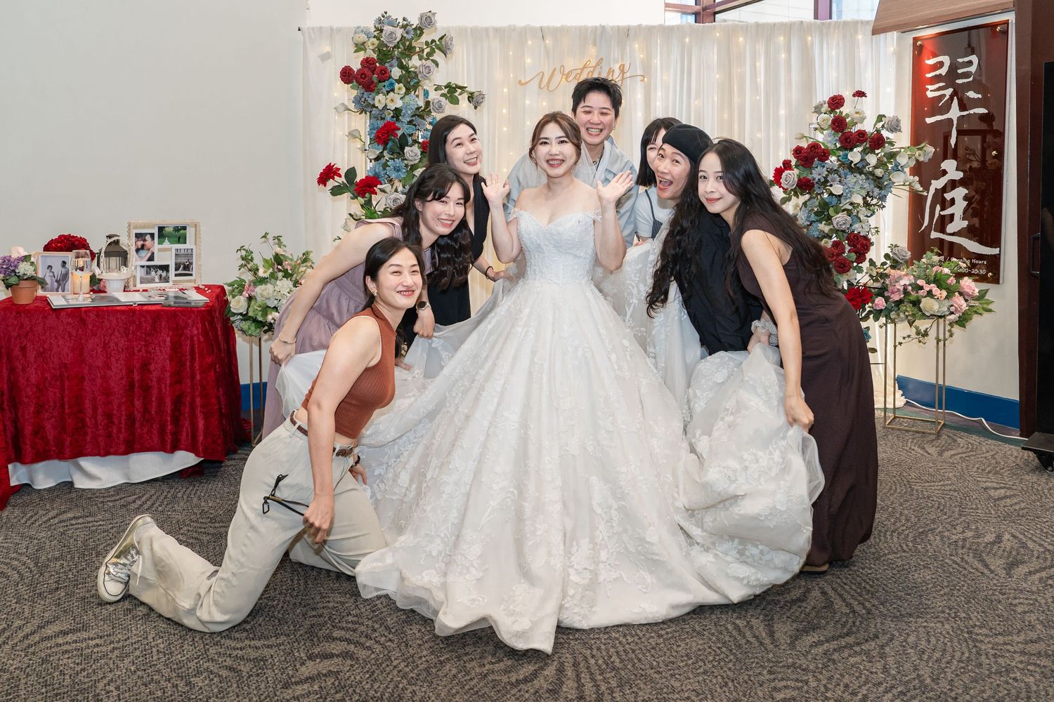 A group in formal attire poses together in a playful dip dance move at a wedding reception.