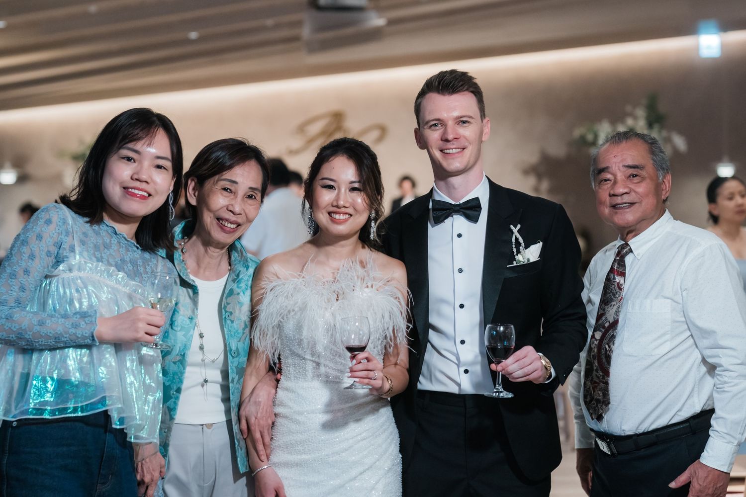 Wedding guests smile while celebrating at a formal reception event in elegant attire.