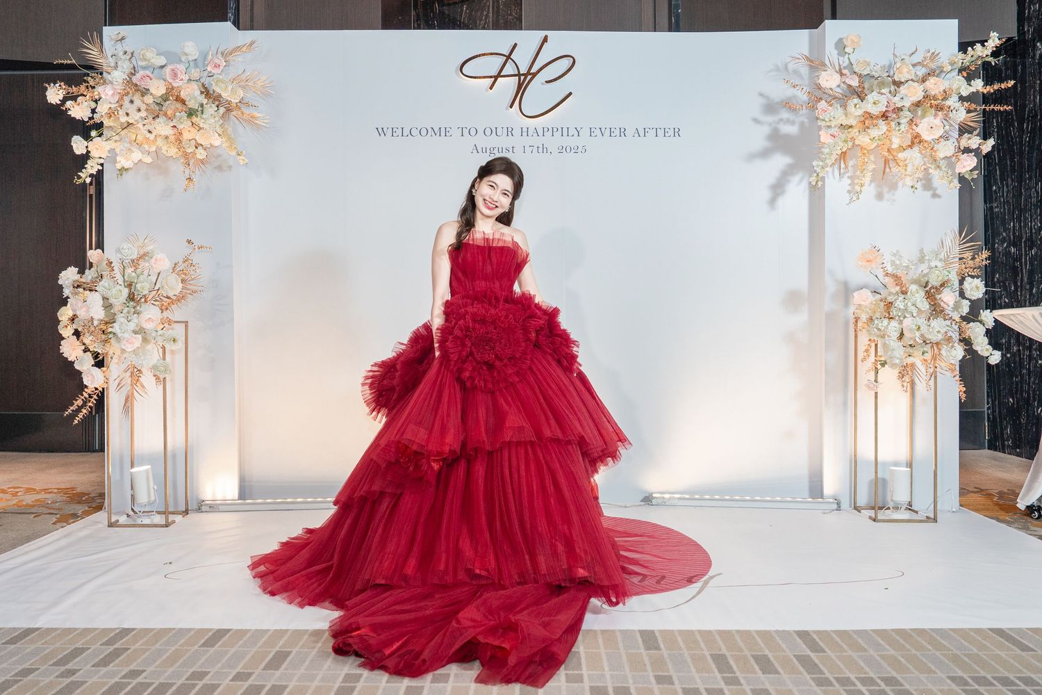 A stunning red ball gown with voluminous ruffled tulle skirt photographed in an elegant white studio setting.