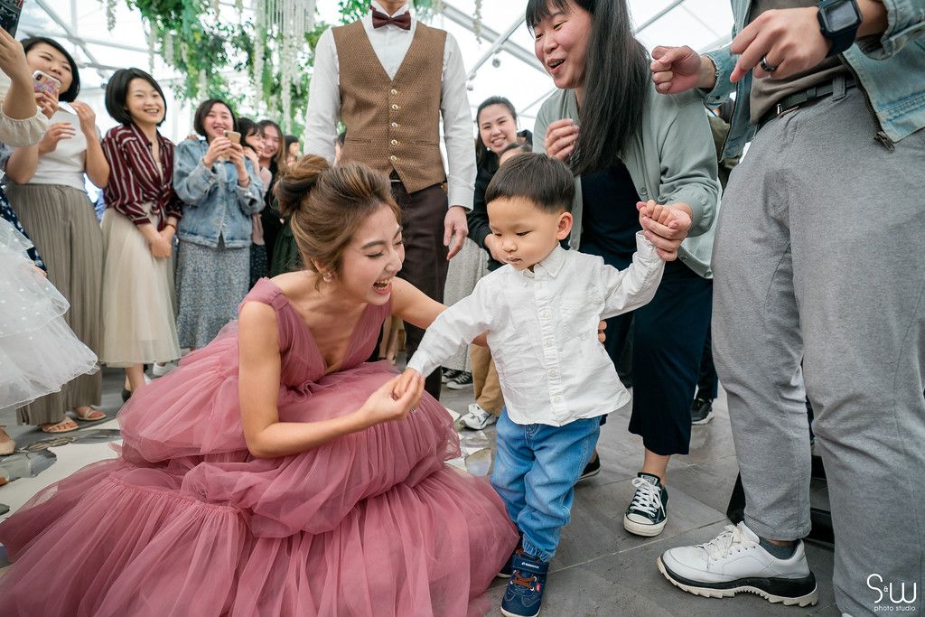 A heartwarming moment as someone in a pink dress interacts with a small child at a celebratory event.