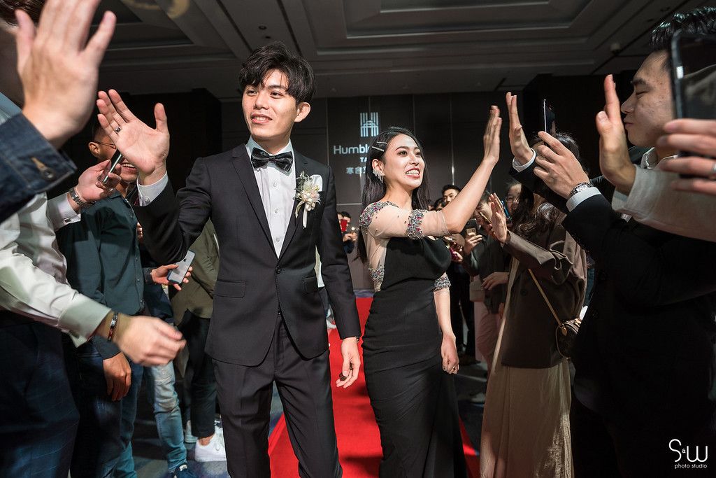 Wedding celebration with guests cheering and taking photos in a formal venue.