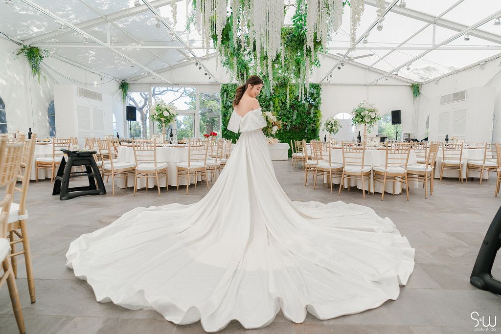 Spectacular cathedral-length wedding gown displayed in a light-filled reception space with green accents.