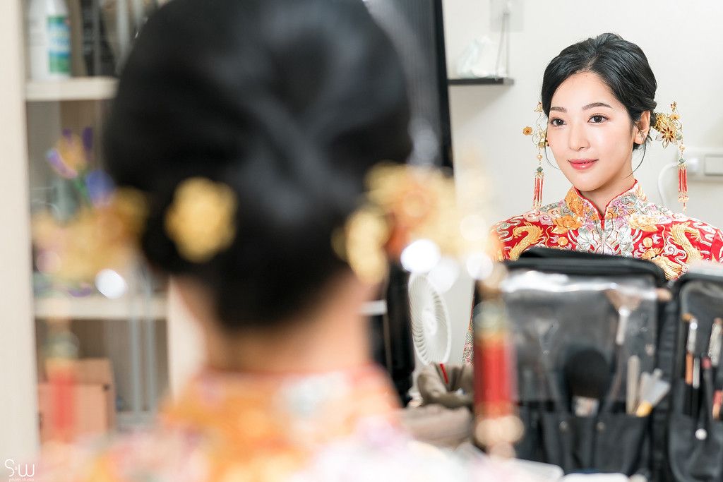 A reflection in a mirror shows someone getting ready while wearing traditional Chinese wedding attire.