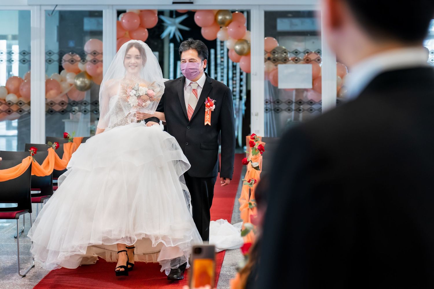 Newlyweds make their entrance on red carpet with festive decorations.