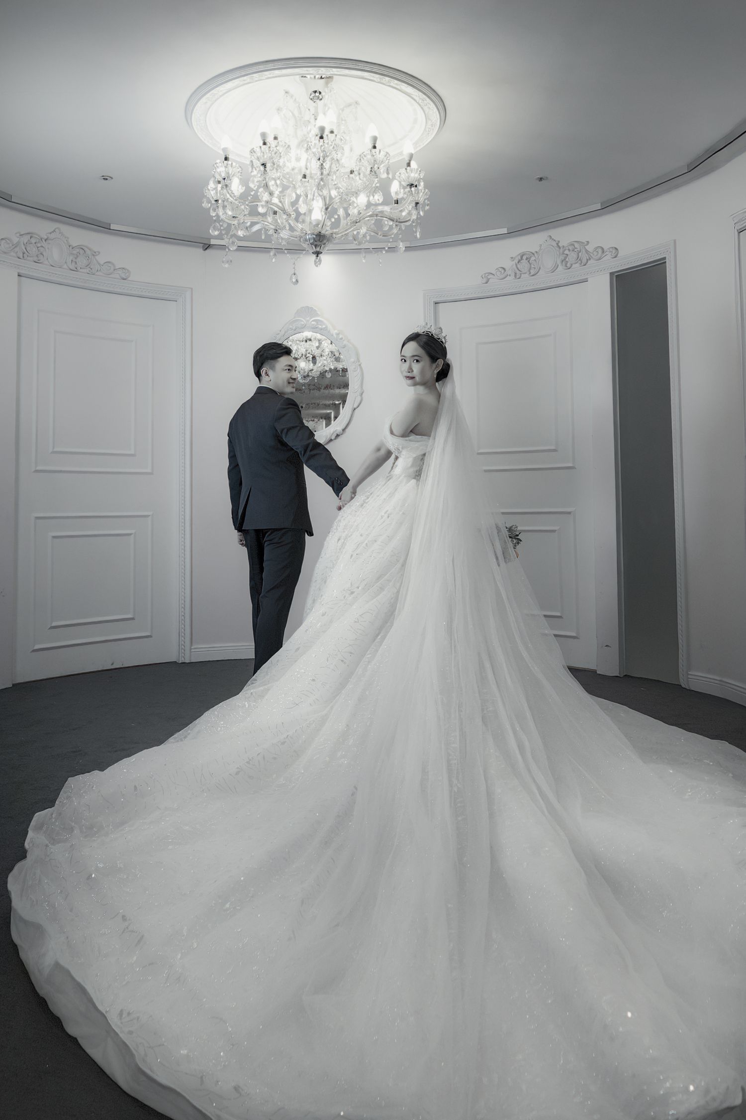 Elegant wedding photoshoot series showing flowing white ballgown dress with cathedral train in luxurious white room.