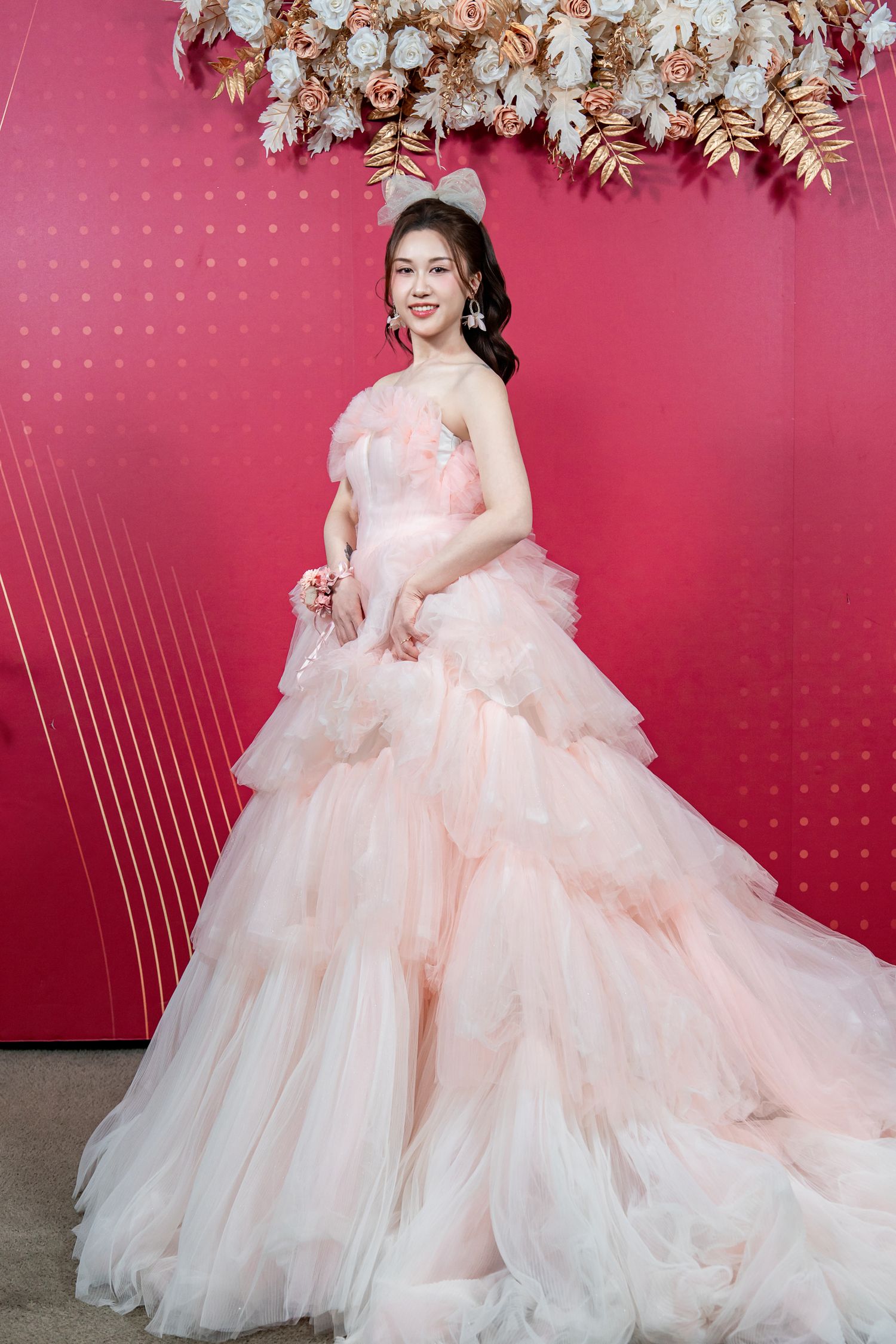 A romantic pink and white tulle ballgown with layered ruffles photographed against a pink backdrop in multiple angles.