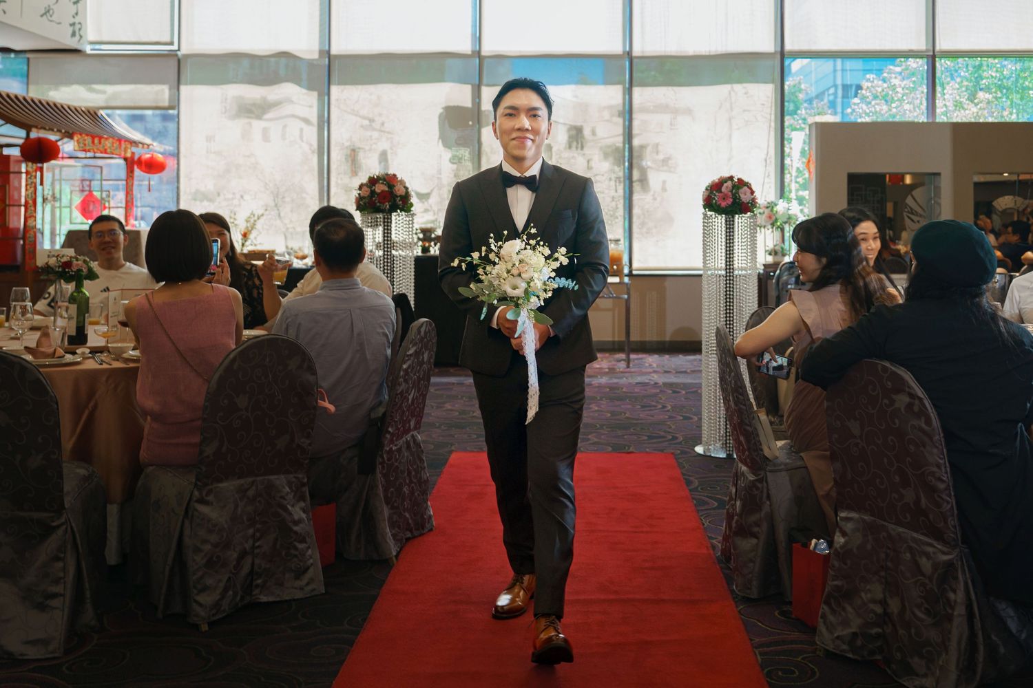 A panoramic view of a business conference room with people seated at tables along a red carpeted aisle.