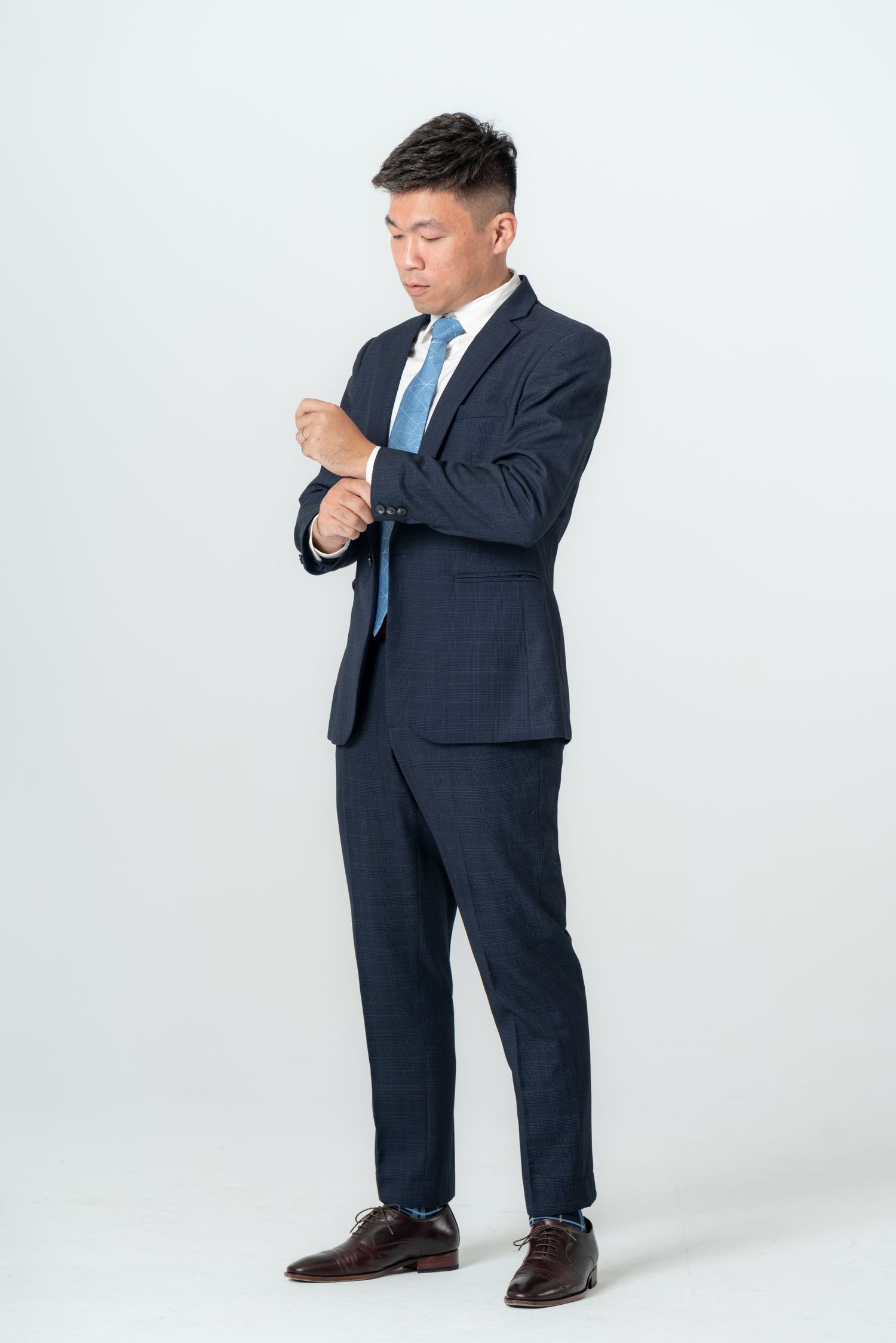 Professional in a navy business suit stands thoughtfully against a white studio backdrop in three different poses.